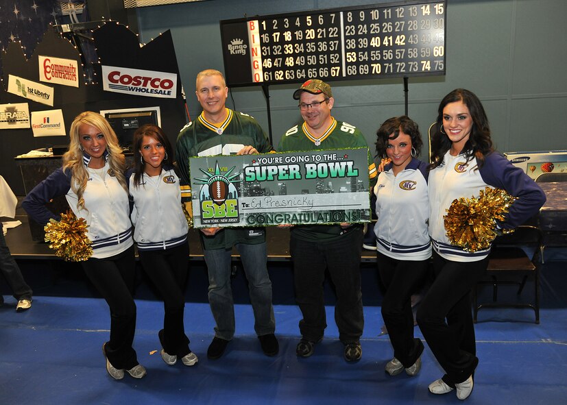 Col. Paul Bauman (left), 319th Air Base Wing commander and Ed Prasnicky (right), 319th Force Support Squadron civilian training technician, pose  with four members of the Minnesota Vikings cheerleading team while holding up a congratulatory sign recognizing Prasnicky as the grand prize winner of the 2014 Super Bowl Extravaganza, which was held, Jan. 18, 2014 at the Fitness Center on Grand Forks Air Force Base, N.D. Prasnicky won an all-expenses-paid trip to Super Bowl XLVIII, which is scheduled to take place Feb. 2, 2014, in East Rutherford, N.J. (U.S. Air Force photo/ Senior Airman Xavier Navarro)