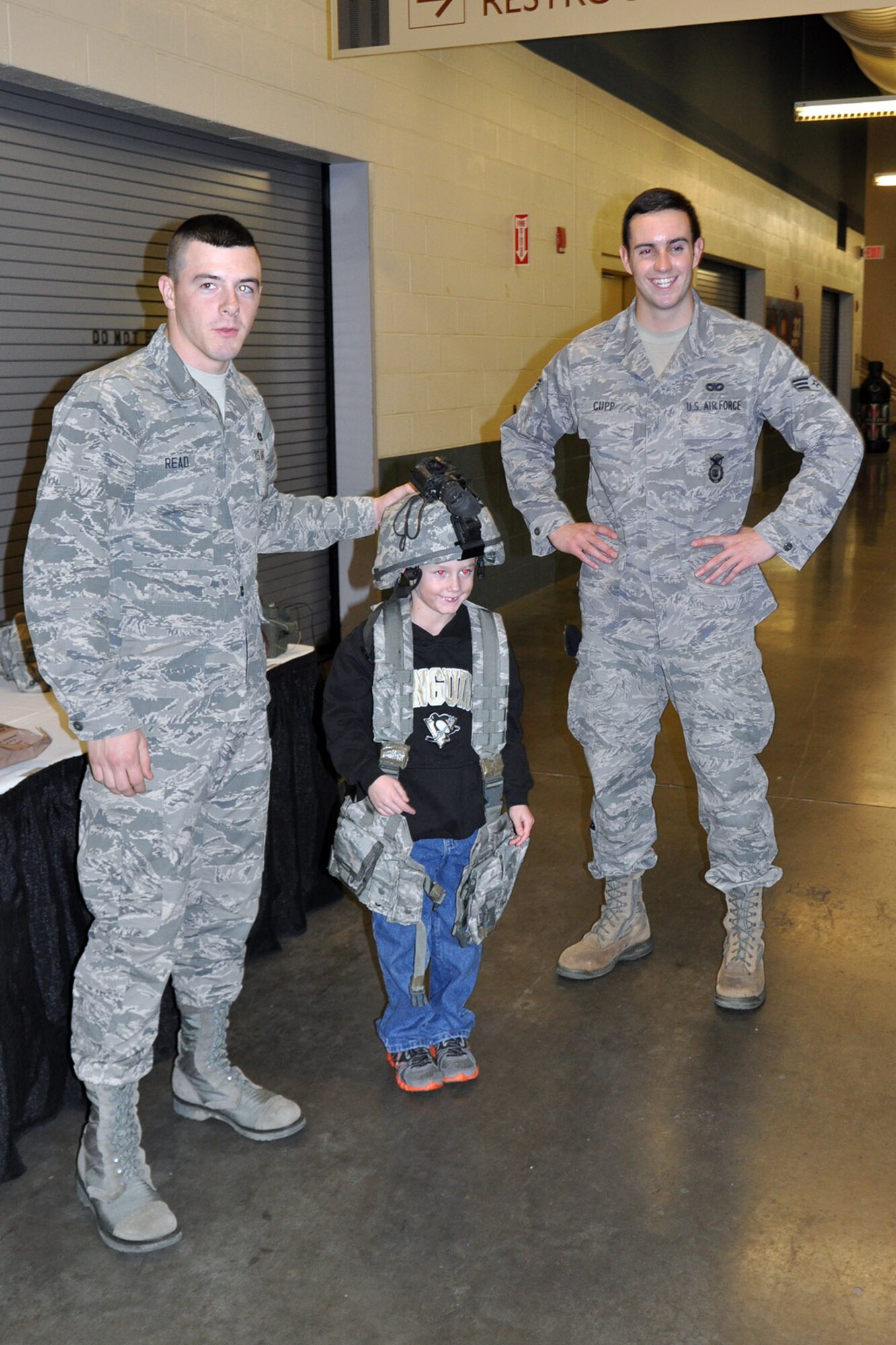 YOUNGSTOWN, Ohio -- Air Force Reserve Airman Basic Jimmy Read and Senior Airman Tyler, both assigned to 910th Security Force Squadron, stand with a young fan who is trying on a helmet and a body armor vest during pre-game festivities for a Youngstown Phantoms hockey game at the Covelli Centre here, Jan. 11, 2014. Nearly 100 Citizen Airmen, based at nearby Youngstown Air Reserve Station, Ohio, participated in YARS Night Out activities before and during the game. The Phantoms, a member of the United States Hockey League, defeated Team USA 6-3 in front of a crowd of more than 1200 people. U.S. Air Force photo by Master Sgt. Bob Barko Jr.
