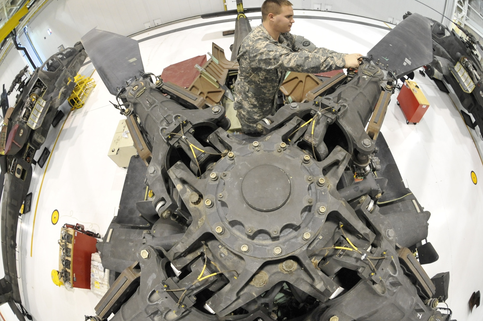 U.S. Army Spc. Todd Gann, 1-135th Attack/Reconnaissance Battalion aircraft maintainer, inspects the main rotor head of an AH-64 Apache at Whiteman Air Force Base, Mo., Jan. 9, 2014. Soldiers perform this inspection annually to ensure there are no signs of corrosion developing, which could cause malfunctions. (U.S. Air Force photo by Airman 1st Class Keenan Berry/Released)