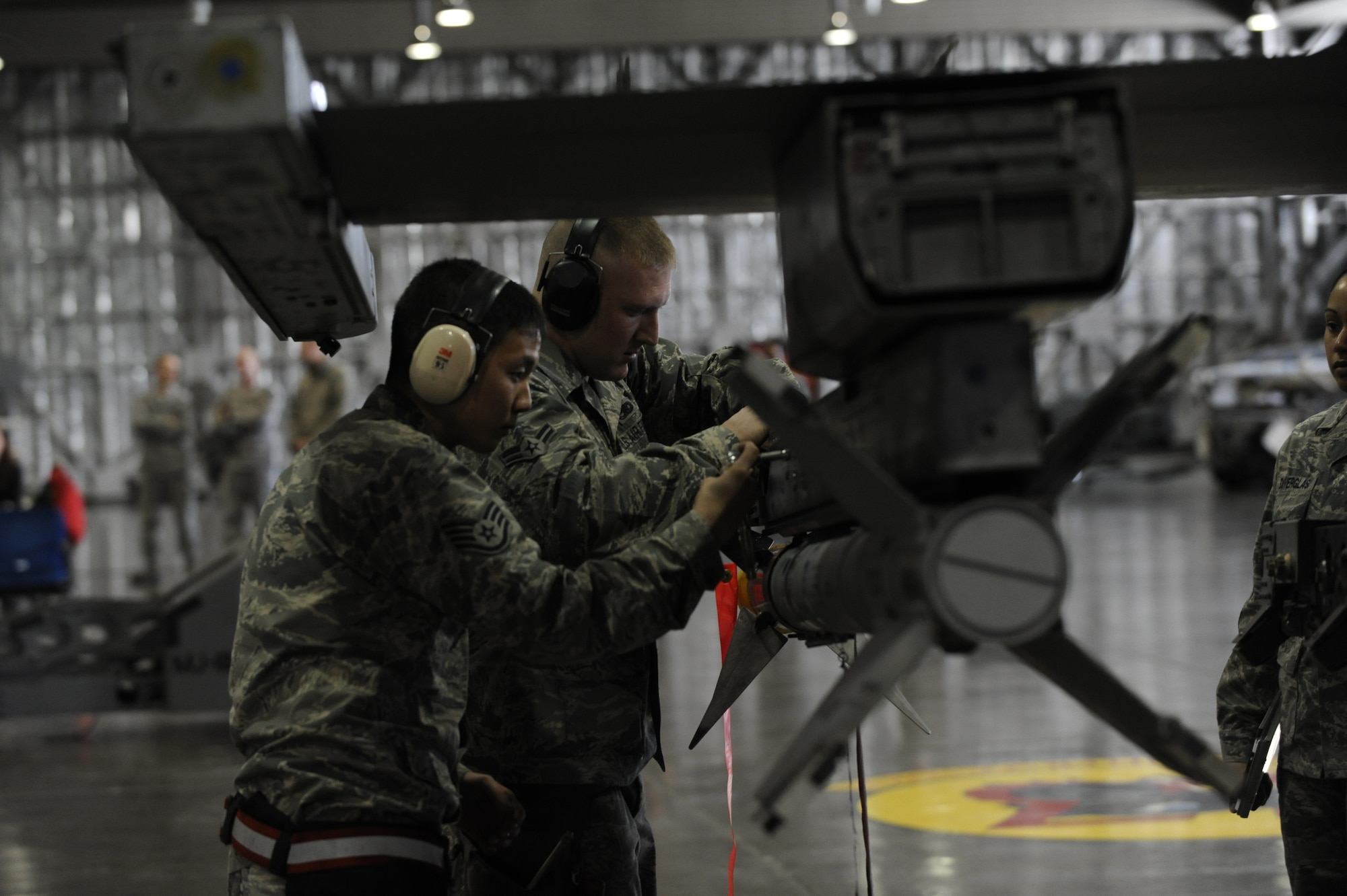 Staff Sgt. Stephan Kim and Airman 1st Class Michael Howell, members of the 13th Aircraft Maintenance Unit weapons load crew, work together to install an armament onto an F-16 Fighting Falcon during the Weapons Load Crew of the Year competition at Misawa Air Base, Japan, Jan. 17, 2014. The team competed against the 14th AMU, where both teams had 40 minutes to complete their weapons loading. (U.S. Air Force photo/Airman 1st Class Patrick S. Ciccarone)