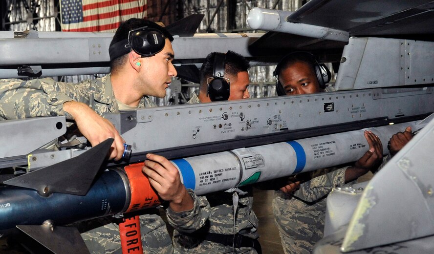 Airman 1st Class Jesse Garza, Staff Sgt. Gregorio Luis and Senior Airman Rashad Holmes, 14th Aircraft Maintenance Unit weapons load crew  members, load an AIM-9 Sidewinder onto an F-16 Fighting Falcon during the Weapons Load Crew of the Year competition at Misawa Air Base, Japan, Jan. 17, 2014. Three-man load crews representing the 13th and 14th AMU battled it out to see who would earn the title of Weapons Load Crew of the Year. (U.S. Air Force photo by Airman 1st Class Zachary Kee)