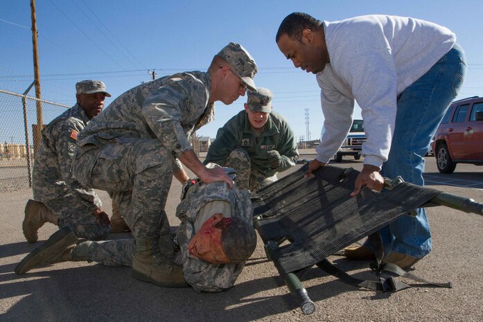 Joaquin Tucker (right) a contract specialist with the U.S. Army Engineering and Support Center, Huntsville, positions a litter to assist Air Force 2nd Lt. Danny Monroe, contract specialist with the 56th Contracting Squadron, Luke Air Force Base, Ariz., with moving a mannequin onto a litter during training at the Fort Bliss Medical Support Training Center, Fort Bliss, Texas. Almost every participant of the Operational Contract Support Joint Exercise 2014 received two full days of medical training as the joint contingency contracting exercise scenario focused on responding to those needing help during a natural disaster. 