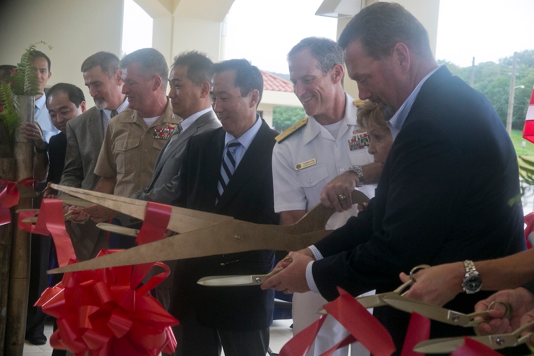 Senior Executive Services Bryan H. Wood, Director, Pacific Division of Plans, Policies, Operations department for Headquarters Marine Corps, Congresswoman Madeleine Z. Bordallo, Rear Admiral Tilghman D. Payne, Joint Region Marianas Commander, Roger M. Natsuhara, Principal Deputy Assistant Secretary of the Navy, Sadaaki Tabei, Deputy Director General for Realignment Initiatives, Colonel Philip Zimmerman, Officer in Charge of marine Corps Activity Guam and Joseph D. Ludovici, Deputy Assistant Secretary of the Navy, Infrastructure Strategy and Analysis, cuts the ribbon for the ceremony for the completion of the first two Marine Corps relocation projects on Naval Base Guam, Jan 22, 2014.  The USMC-funded Apra Harbor Wharf Improvement and the Government of Japan-funded USMC Welcome Center projects total more than $80 million in construction.