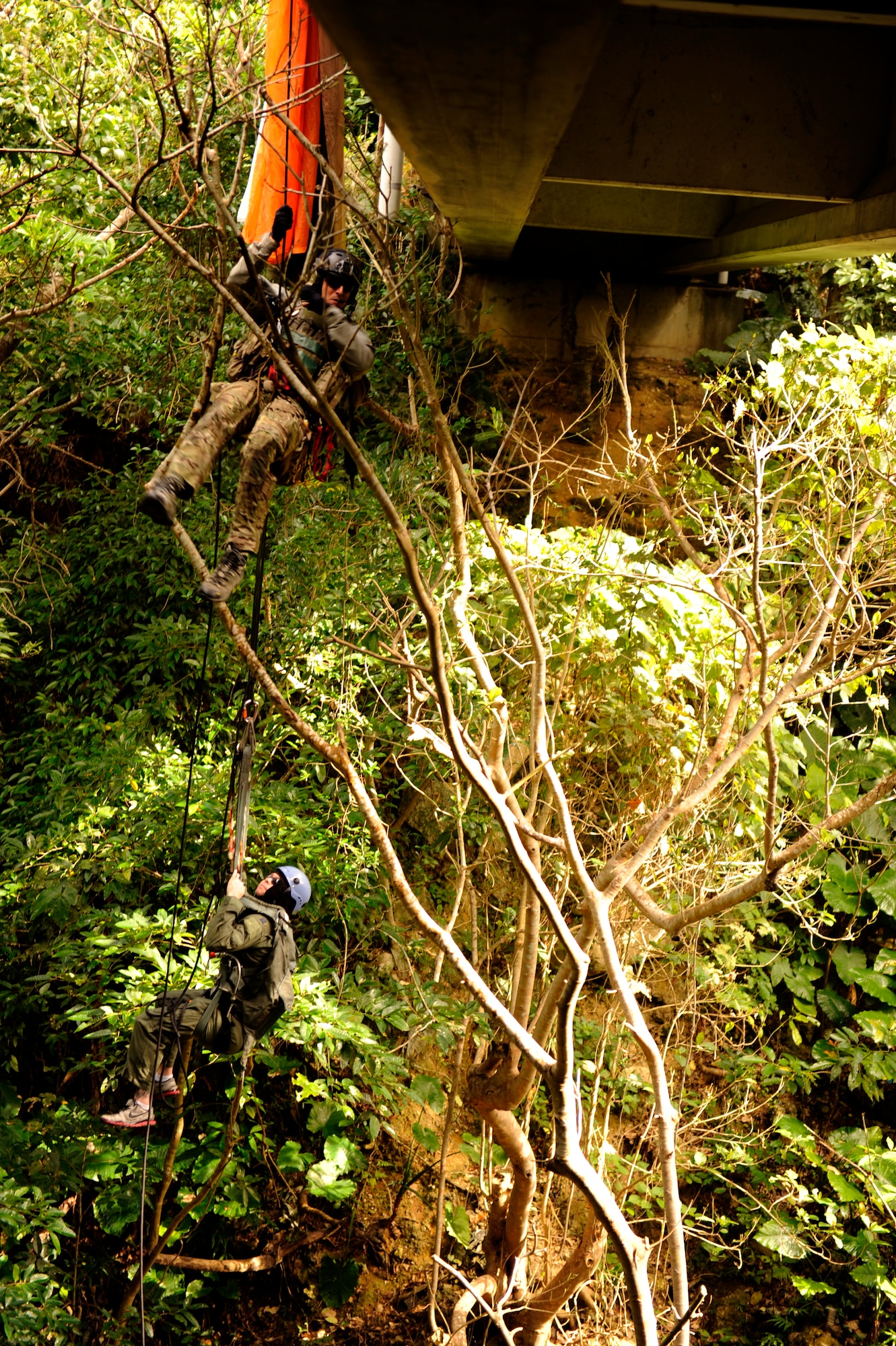 U.S. Air Force Staff Sgt. Joshua Cunningham, 31st Rescue Squadron pararescueman, rappels from a bridge to save Staff Sgt. George Reed, 31st RQS pararescueman and simulated parachute catch victim, during element leader upgrade training on Kadena Air Base, Japan, Jan. 22, 2014. Pararescuemen frequently train in a multitude of rescue scenarios in order to be prepared for any environment or situation and maintain proficiency. (U.S. Air Force photo by Senior Airman Maeson L. Elleman)
