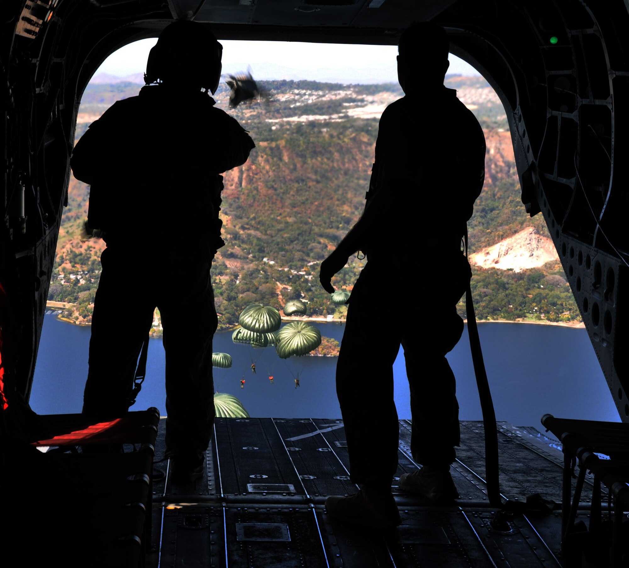 A crewchief and jumpmaster watch as U.S. Special Forces and El Salvadoran military members maneuver under canopy after jumping from the ramp of a CH-47 Chinook helicopter at an altitude of 1,250 feet during a joint airborne operations training exercise conducted by U.S. Special Forces and El Salvadoran servicemembers over Lake Ilopango, El Salvador, Jan. 21, 2014.  U.S. Special Forces from the 7th Special Forces Group (Airborne) conducted the training exercise alongside members of the El Salvadoran military.  The joint-training, overwater static jump allowed members from both nations to maintain currency while strengthening the relationship between the U.S. and El Salvadoran forces.  Joint Task Force-Bravo’s 1-228th Aviation Regiment provided aerial support for the exercise, flying each chalk of jumpers from the Ilopango International Airport to the drop zone over Lake Ilopango.  (U.S. Air Force photo by Capt. Zach Anderson)