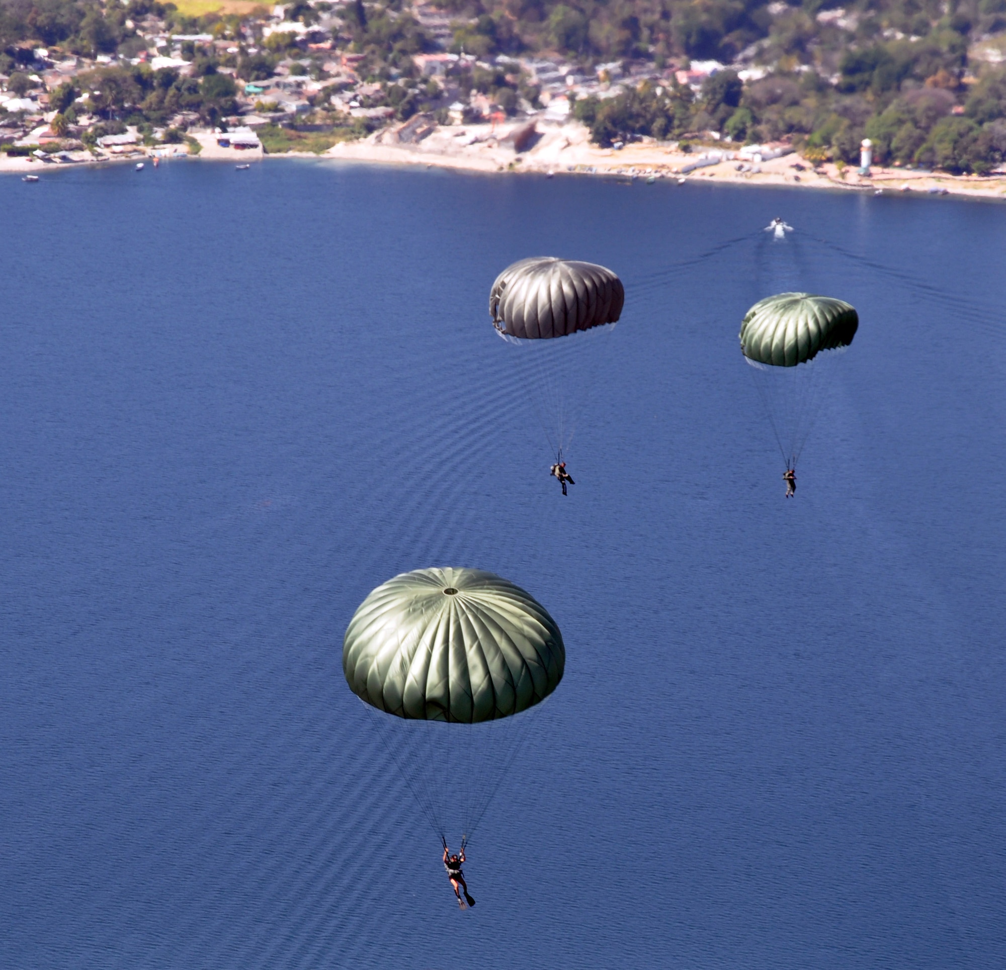 U.S. Special Forces and El Salvadoran military members maneuver under canopy after jumping from the ramp of a CH-47 Chinook helicopter at an altitude of 1,250 feet during a joint airborne operations training exercise conducted by U.S. Special Forces and El Salvadoran servicemembers over Lake Ilopango, El Salvador, Jan. 21, 2014.  U.S. Special Forces from the 7th Special Forces Group (Airborne) conducted the training exercise alongside members of the El Salvadoran military.  The joint-training, overwater static jump allowed members from both nations to maintain currency while strengthening the relationship between the U.S. and El Salvadoran forces.  Joint Task Force-Bravo’s 1-228th Aviation Regiment provided aerial support for the exercise, flying each chalk of jumpers from the Ilopango International Airport to the drop zone over Lake Ilopango.  (U.S. Air Force photo by Capt. Zach Anderson)