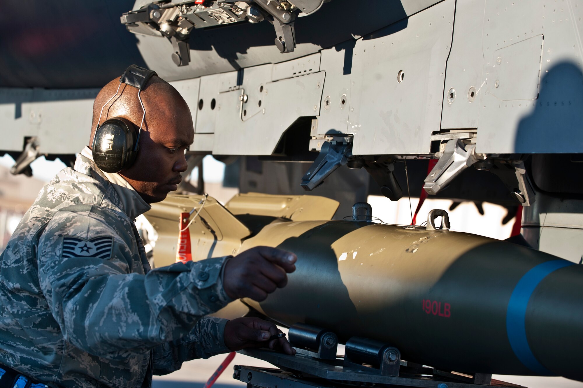 Tech. Sgt. Thomas Holmes, 757th Aircraft Maintenance Squadron Strike Aircraft Maintenance Unit weapons load crew chief, guides an inert Mark-82 bomb onto an F-15E Strike Eagle during the annual load crew competition on the flightline Jan. 17, 2014, at Nellis Air Force Base, Nev. Load crew competitions take place every quarter as well as annually. (U.S. Air Force photo by Senior Airman Matthew Lancaster)