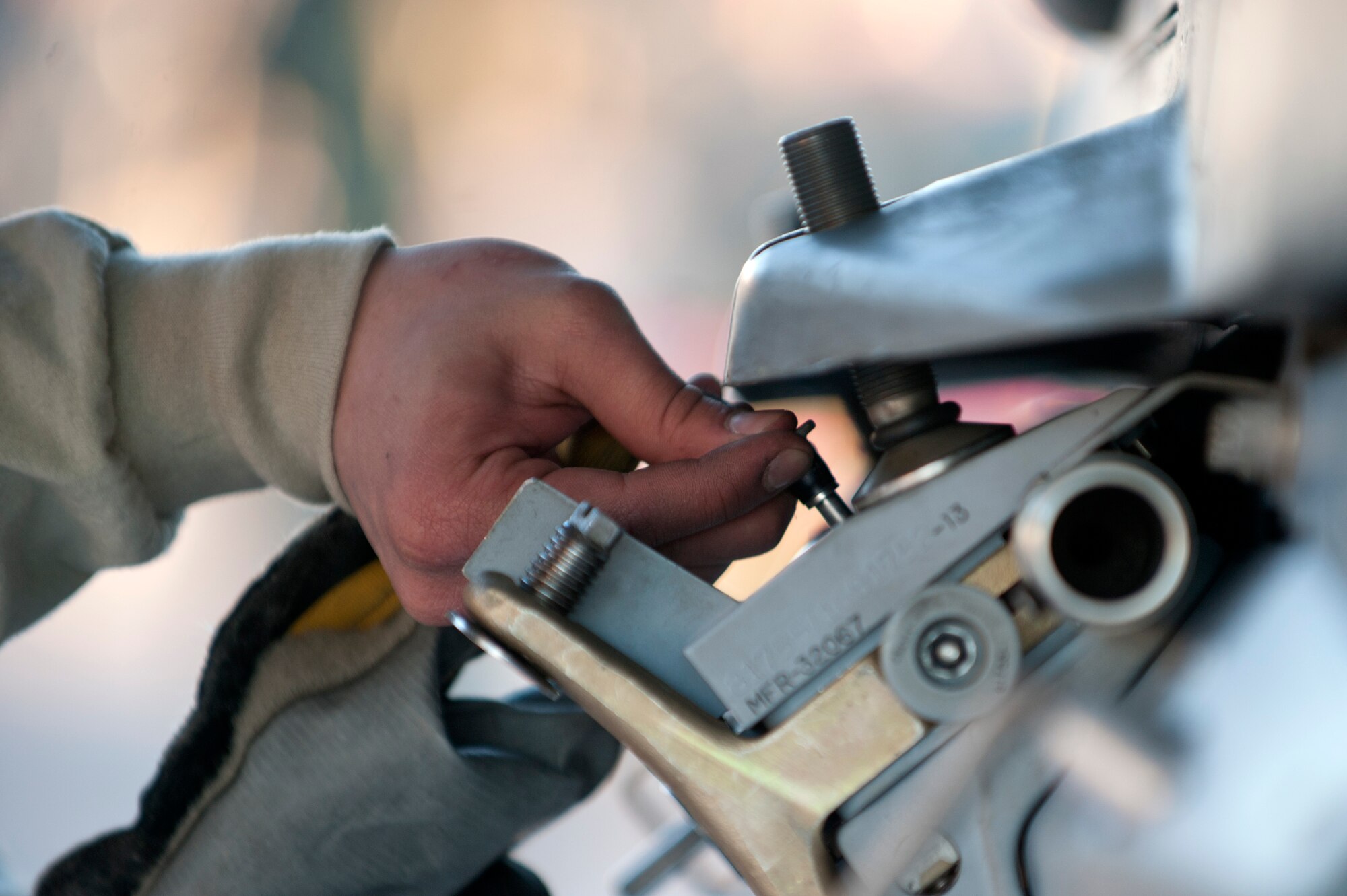 Airman 1st Class Dwight Mallari, 57th Aircraft Maintenance Squadron Tomahawk Aircraft Maintenance Unit load crew member, attaches a pin to an F-16 Fighting Falcon during the annual load crew competition on the flightline Jan. 17, 2014, at Nellis Air Force Base, Nev. Weapons load teams are evaluated for use of the checklist, safety and overall speed. (U.S. Air Force photo by Senior Airman Matthew Lancaster)