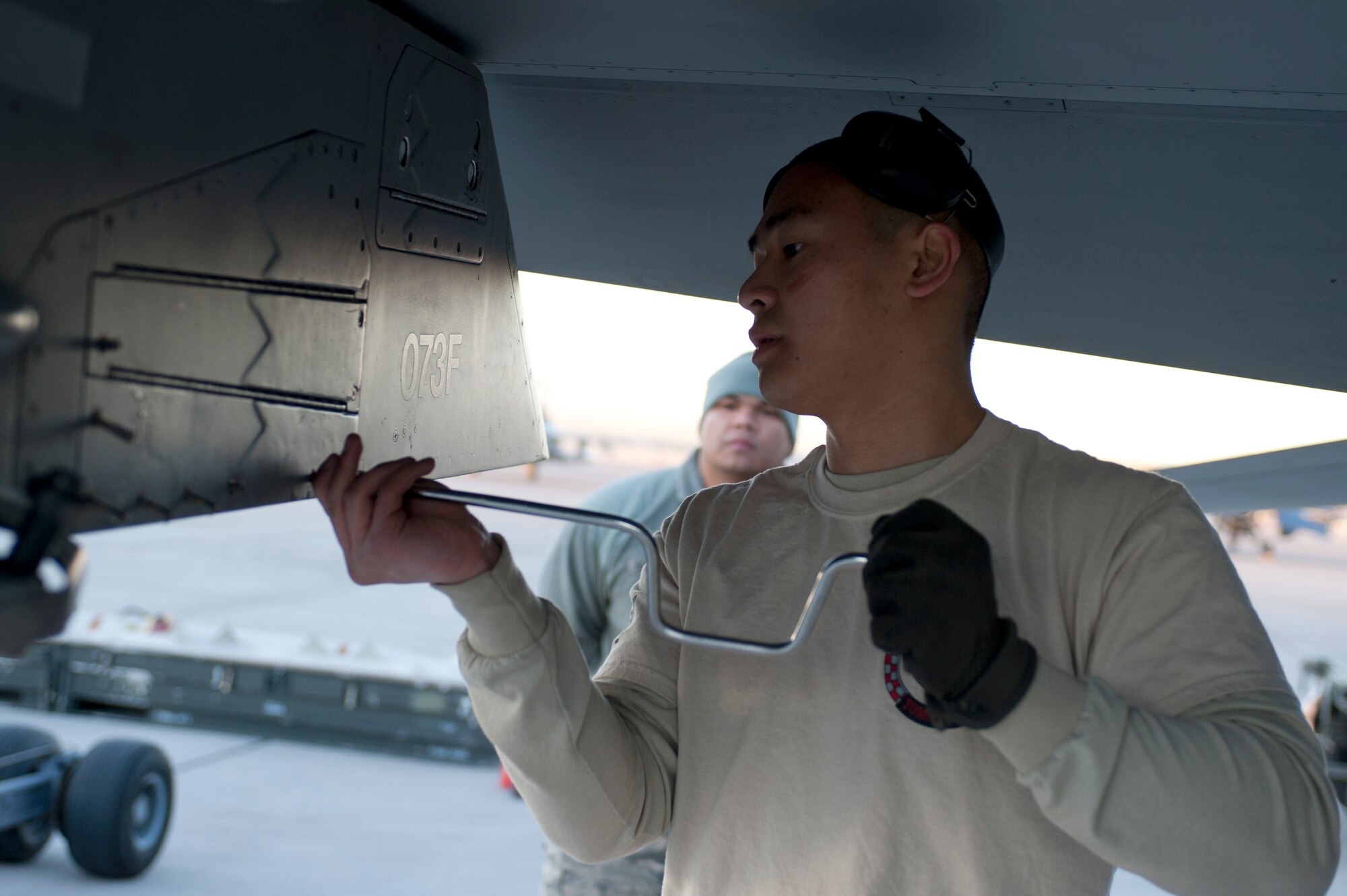 Airman 1st Class Dwight Mallari, 57th Aircraft Maintenance Squadron Tomahawk Aircraft Maintenance Unit load crew member, loosens screws in preparation to load inert munitions onto an F-16 Fighting Falcon during the annual load crew competition on the flight line Jan. 17, 2014, at Nellis Air Force Base, Nev. The load crew competition boosts morale and promotes an environment of friendly competition. (U.S. Air Force photo by Senior Airman Matthew Lancaster)