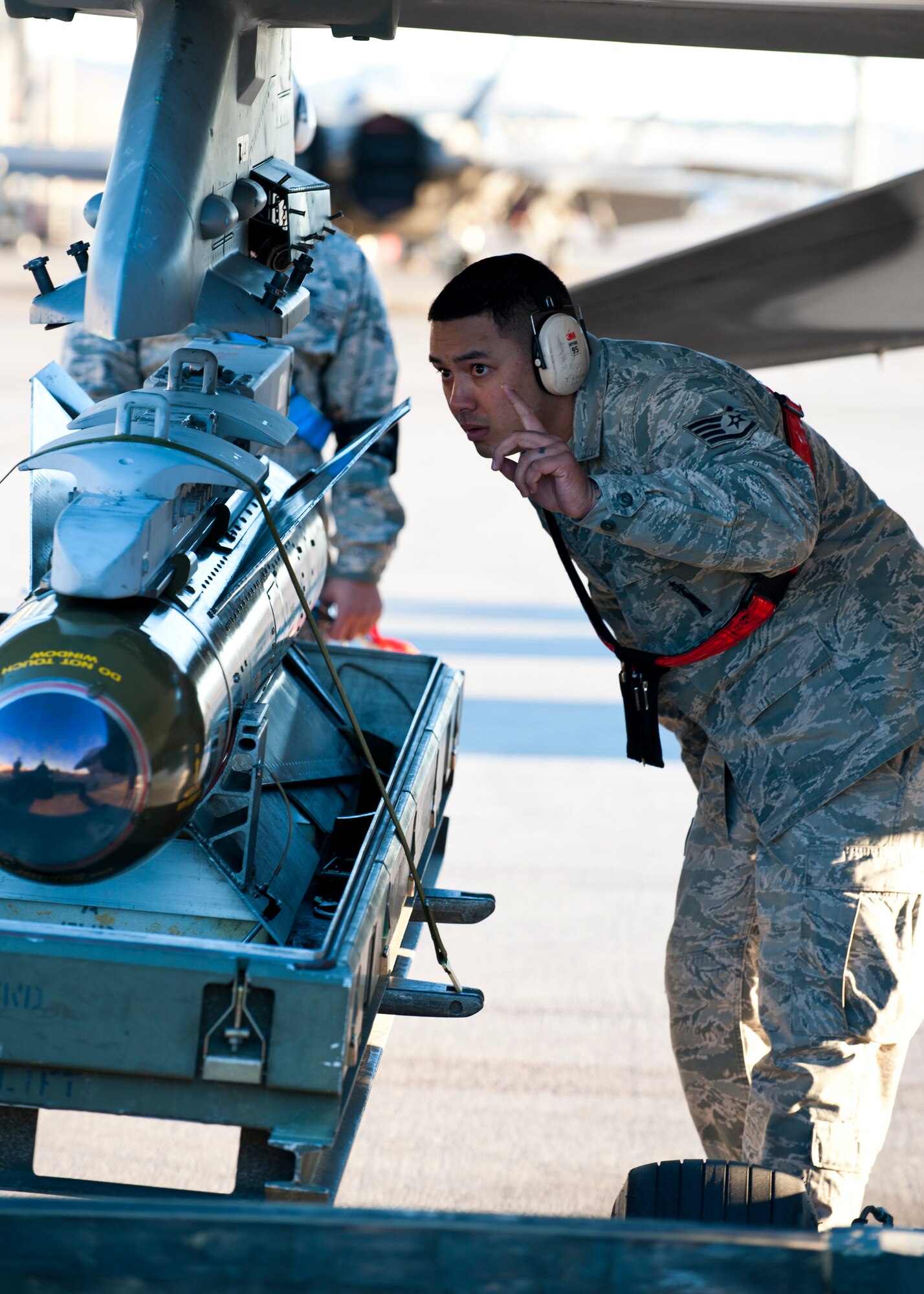 U.S. Air Force Staff Sgt. Treston Kaneao, 57th Aircraft Maintenance Squadron Viper Aircraft Maintenance Unit weapons load crew chief, directs the loading of inert munitions during the annual weapons load crew competition on the flightline Jan. 17, 2014, at Nellis Air Force Base, Nev. Load crew competitions are held to sharpen Airmen’s skills while competing with one another. (U.S. Air Force photo by Airman 1st Class Thomas Spangler)