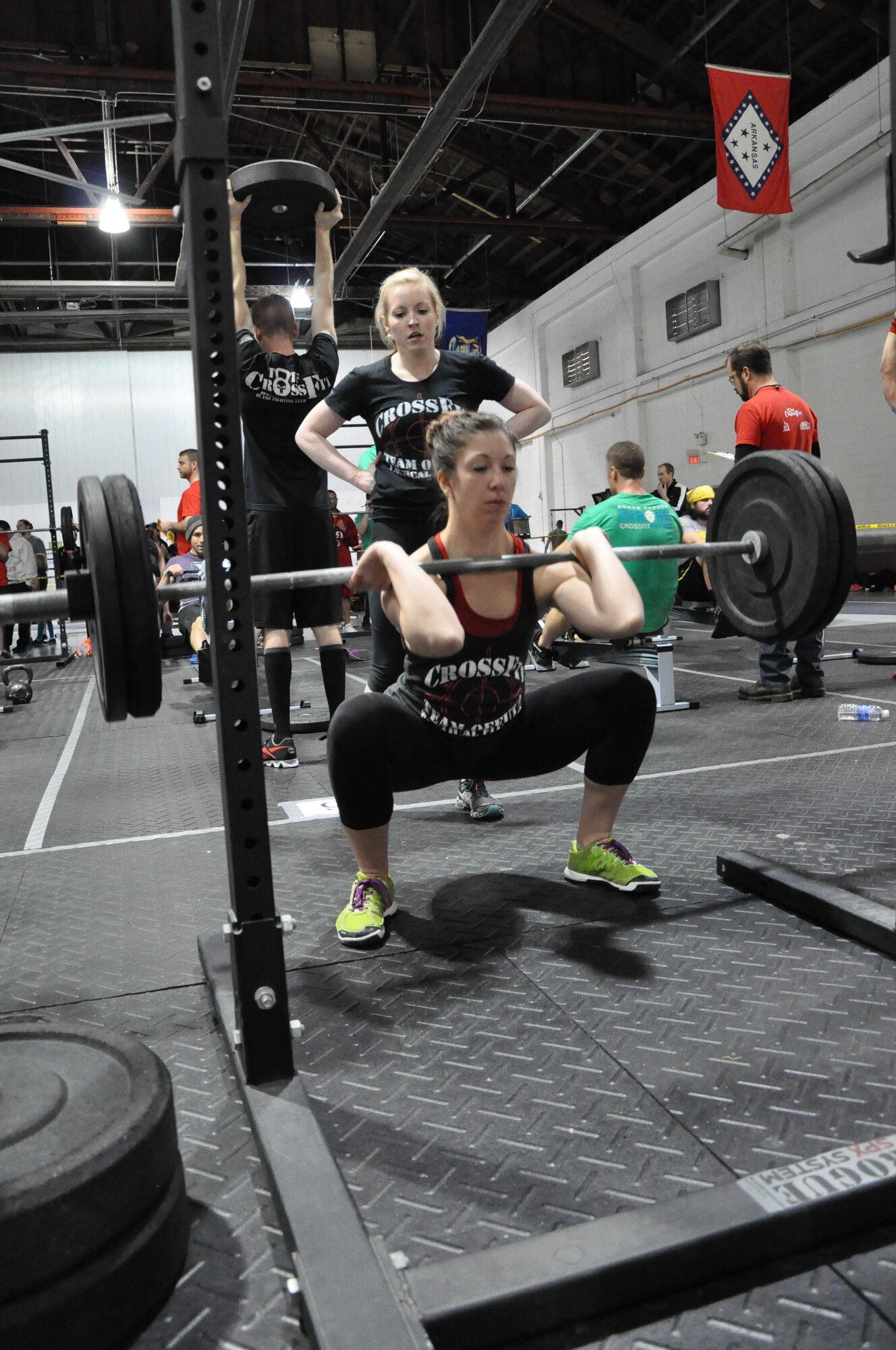 Kimberly Huhmann with Team Offutt Tactical Fitness completes a front squat while her partner Emily Yates cheers her on during the second of three workout of the 2014 TactFit Games at the Offutt Field House Jan. 19. Competitors registered in teams consisting of two males and two females and are divided into two divisions, RX and scaled. RX means all participants must complete the workout as prescribed, doing the same amount of reps with the same amount of weight. Scaled allows competitors to modify their workouts based on their ability. Twenty-five teams will compete in the RX division and 25 teams in the scaled division. (U.S. Air Force Photo by 2nd Lt. Carly A. Costello/Released)
