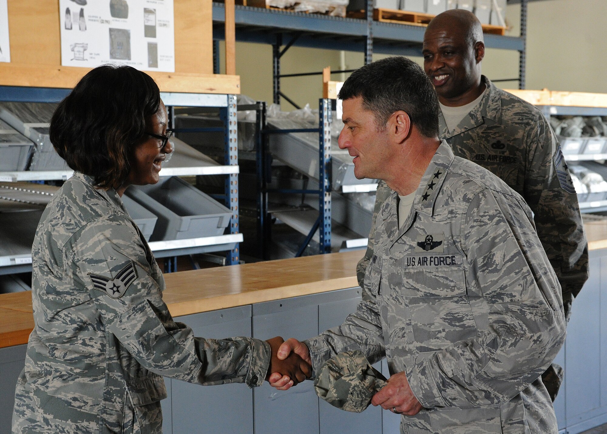 Lt. Gen. Russell Handy, 11th Air Force commander, presents a coin to Senior Airman Latrice Harris, a 647th Logistics Readiness Squadron log planner, at the Personnel Deployment Function building, during a familiarization tour at Joint Base Pearl Harbor-Hickam, Hawaii, Jan. 21, 2014. Harris was recognized for her efforts in the 2013 Consolidated Unit Inspection in which her unit received an excellent rating. (U.S. Air Force photo/Master Sgt. Jerome S. Tayborn) 