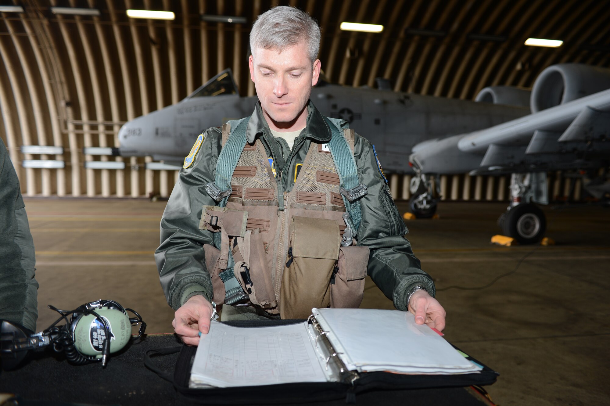 Maj. (Dr.) Jeffrey Woolford, Air Force Institute of Technology student, goes through maintenance forms before taking his second fini-flight in the A-10 Thunderbolt II at Spangdahlem Air Base, Germany, Jan. 17, 2013. At this time, Woolford was an A-10 pilot with the 81st Fighter Squadron at Spangdahlem. Woolford took his first fini-flight when he transitioned into active duty from the Air National Guard to become a pilot-physician.  A fini-flight is a tradition that celebrates a pilot’s final flight in an aircraft. He took two because upon re-entering active duty there was no guarantee that he would return to flight. (U.S. Air Force photo by Staff Sgt. Natasha Stannard)