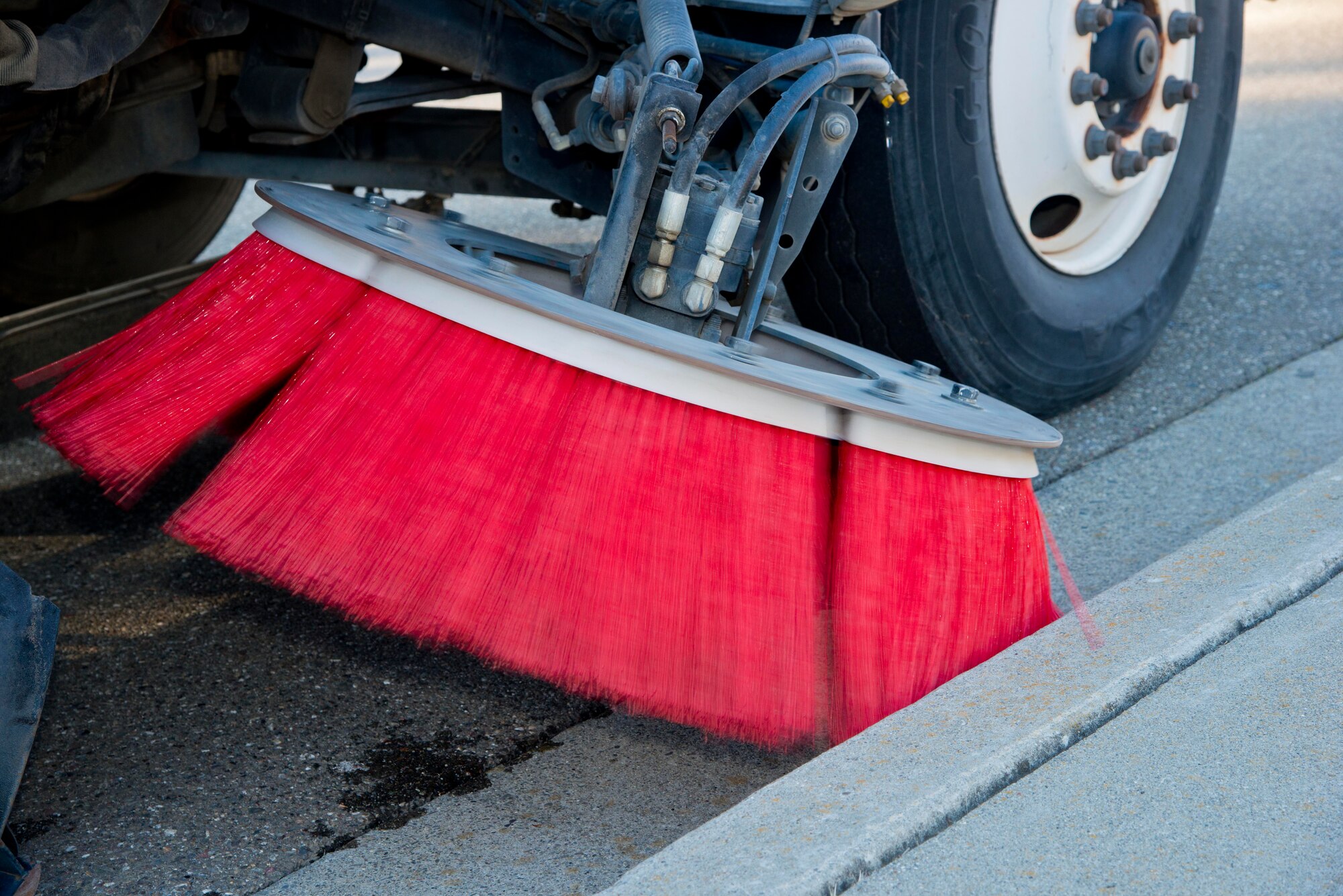 A street sweepers broom works to pick up debris on Tuesday. All the debris
gets vacuumed into a large collection bin at the back of the truck, swept
inside through these two large circular gutter brooms.(U.S. Air Force photo/Senior Airman Nicole Leidholm)