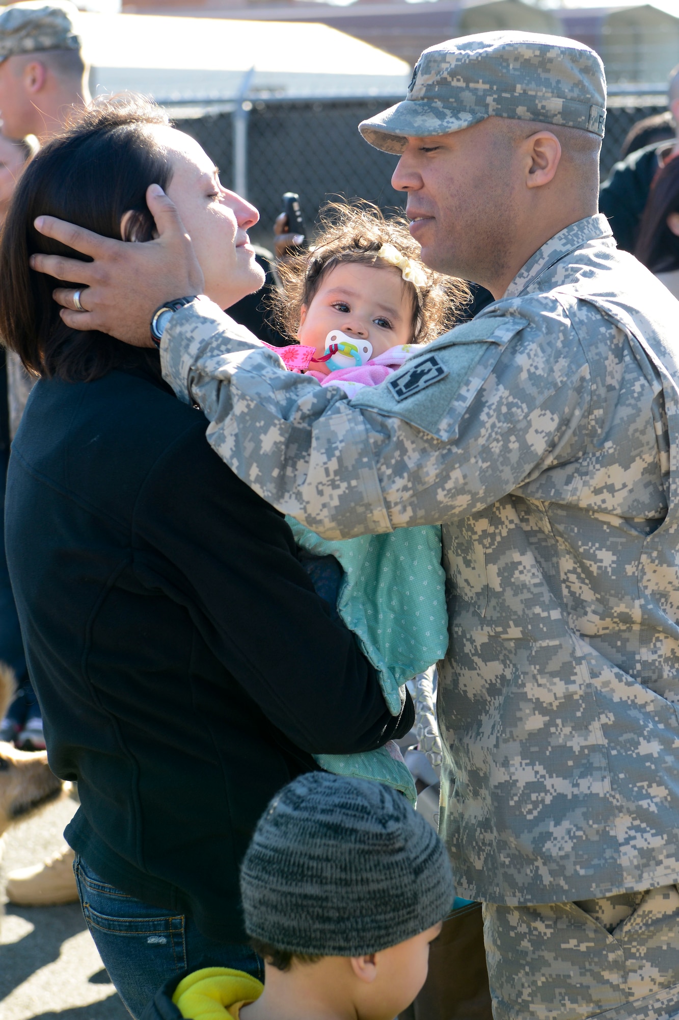 U.S. Army Staff Sgt. Peter Fountain, 511th Engineer Dive Detachment, kisses his wife and children goodbye during a deployment ceremony at Fort Eustis, Va., Jan. 18, 2014. The Soldiers will be part of a theater asset available to complete tasks ranging from hull inspections on Army, Navy and Coast guard vessels to port opening, maintenance and salvage operations. The Fountains hail from Grafton, Mass. (U.S. Air Force photo by Staff Sgt. Ciara Wymbs/Released)