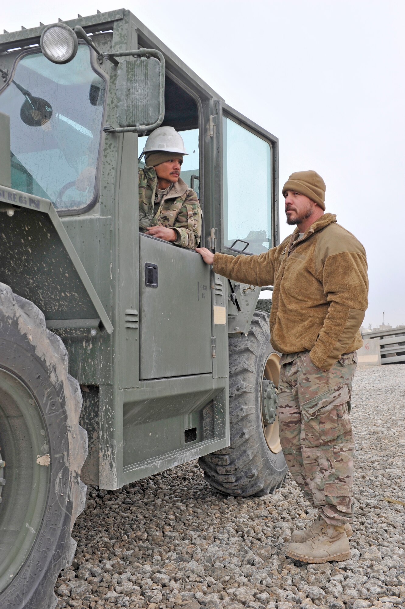 Thomas Ibanez, heavy equipment operator, discusses with Elisha Craft, both U.S. Air Force civilians, how to best employ his foklift to reposition concrete barriers on Bagram Airfield, Afghanistan, Jan. 21, 2014. Ibanez is a native of Guam and deployed from Hill Air Force Base while Craft is deployed from Eglin Air Force Base.(U.S. Air Force photo by Senior Master Sgt. Gary J. Rihn/Released)