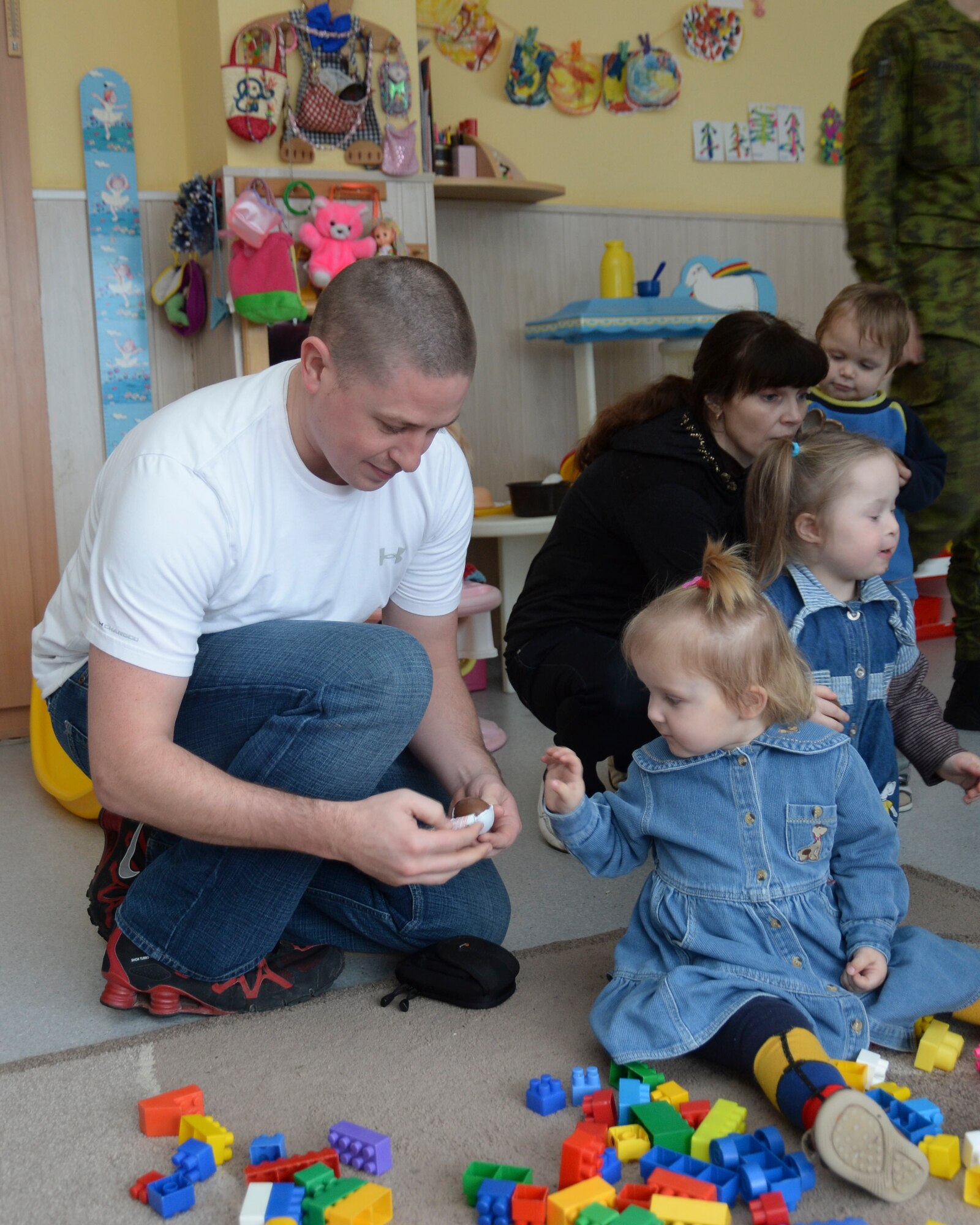 Tech. Sgt. Bryan Stowe, 48th Munitions Squadron NCO in charge of munitions training, opens candy for children at the Šiauliai City Baby’s Orphanage in Lithuania, Jan. 9, 2014. Airmen volunteered during the NATO Baltic Air Policing mission to give back to the host community. (U.S. Air Force photo by Airman 1st Class Nigel Sandridge/Released)