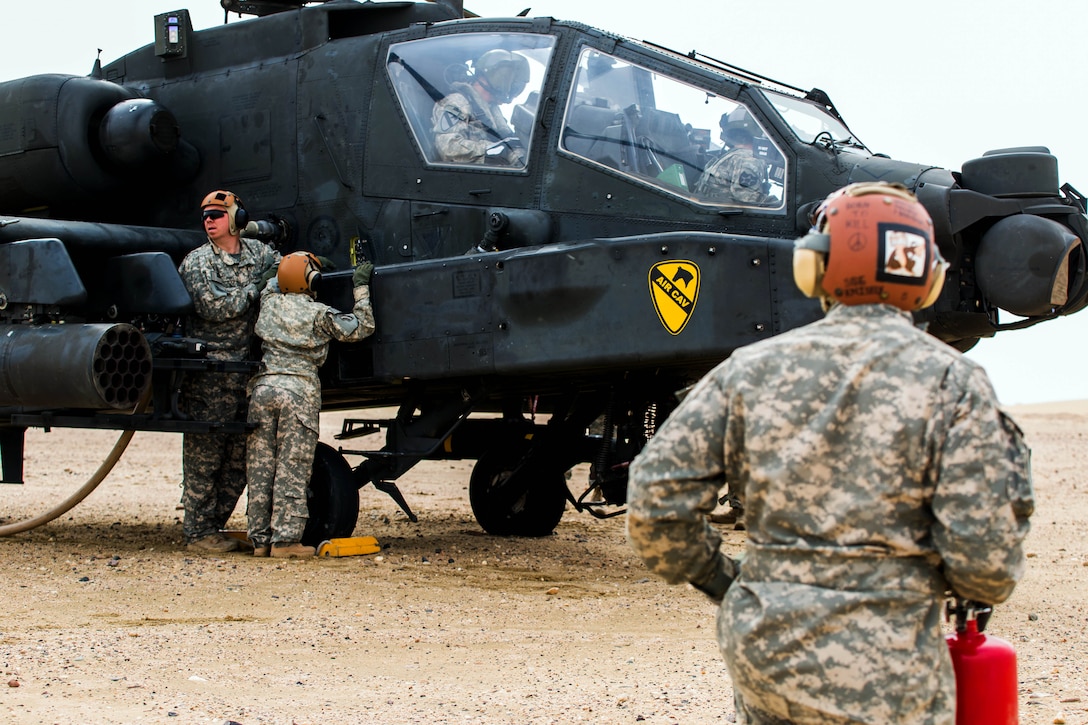 U.S. Army Sgt. Derriff Moncriffe, foreground, stands fire watch while other soldiers fuel an AH-64 Apache helicopter during a forward arming and refueling point exercise near Camp Buehring, Kuwait, Jan. 15, 2014. Moncriffe is assigned to Company A, 642nd Aviation Support Battalion, 42nd Combat Aviation Brigade, and the helicopter crew is assigned to 1st Cavalry Division's 4th Battalion, 227th Attack Reconnaissance Battalion.