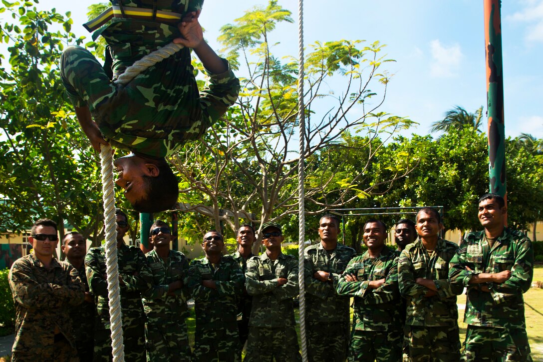 A Maldivian marine shows a rope climbing technique before a squad competition during a noncommissioned officer development program in Maafilaafushi, Maldives, Jan. 21, 2014.