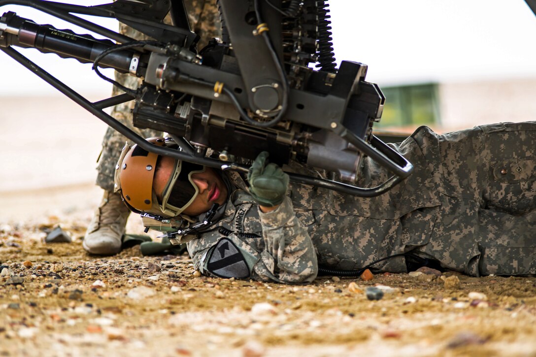 U.S. Army Spc. Armando Ramirez checks an AH-64 Apache helicopter’s M230 30 mm automatic cannon during a forward arming and refueling point exercise near Camp Buehring, Kuwait, Jan. 15, 2014. Ramirez is assigned to 1st Cavalry Division's 4th Battalion, 227th Attack Reconnaissance Battalion.