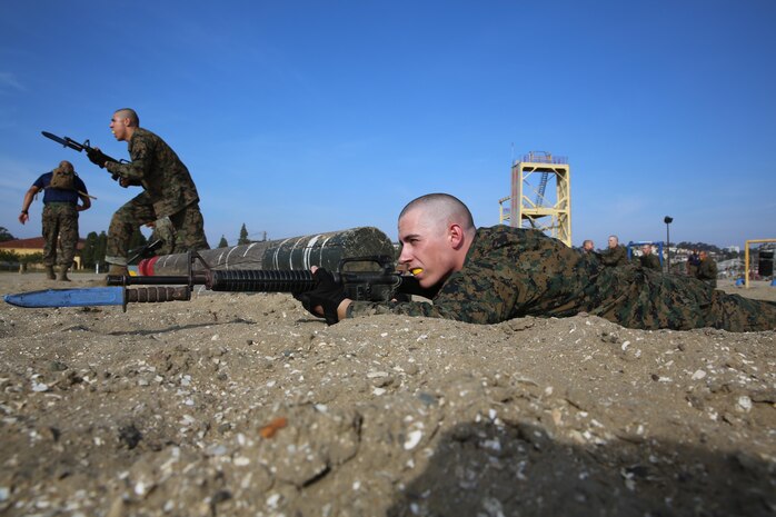 A recruit of Company I, 3rd Recruit Training Battalion, buddy rushes across the sand and takes cover behind a log during the Bayonet Assault Course aboard the depot, Jan. 9. A buddy rush is when two or more Marines move across a terrain while at least one keeps
cover at all times.