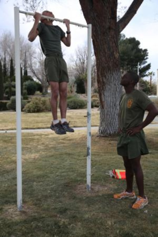 Corporal Samnorp Deung, supply clerk on Marine Corps Logistics Base Barstow, Calif., executes pull-ups as Sgt. Elton Rogers, supply administrative chief here, keeps count and encourages him, Jan. 21. The Marines are preparing for an upcoming Physical Fitness Test.
