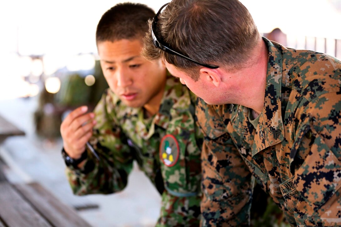 A U.S. Marine, right, pre-sniper instructor, Division Schools, discusses logistics with a soldier from the Japan Ground Self-Defense Force while conducting land navigation training during Exercise Iron Fist 2014 aboard Camp Pendleton, Calif., Jan. 22, 2014. Iron Fist is an amphibious exercise that brings together Marines and sailors from the 15th Marine Expeditionary Unit, other I Marine Expeditionary Force units, and soldiers from the JGSDF, to promote military interoperability and hone individual and small-unit skills through challenging, complex and realistic training. (U.S. Marine Corps photo by Lance Cpl. Ricardo Hurtado/Released)