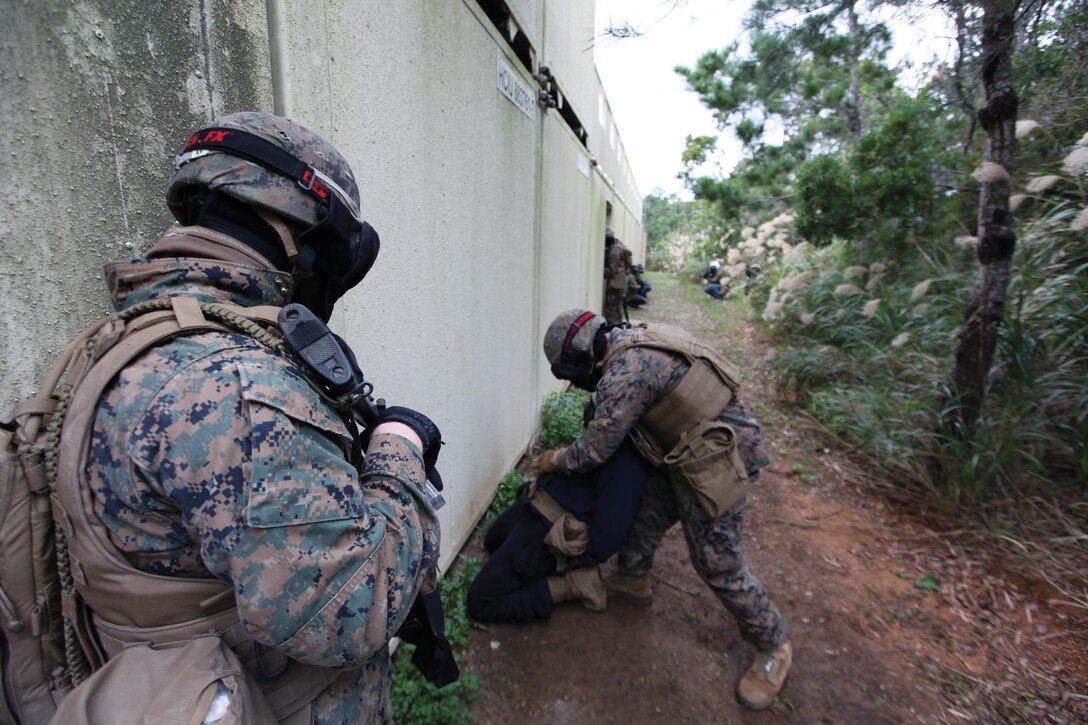 A Marine with 3rd LE Bn. searches and secures a simulated enemy combatant while another provides security Jan. 16 during MOUT training at Combat Town in the Central Training Area. Marines with the battalion perfected a variety of skill-sets from patrolling to room clearing in preparation for future operations and exercises, as well as increasing their overall combat readiness. 