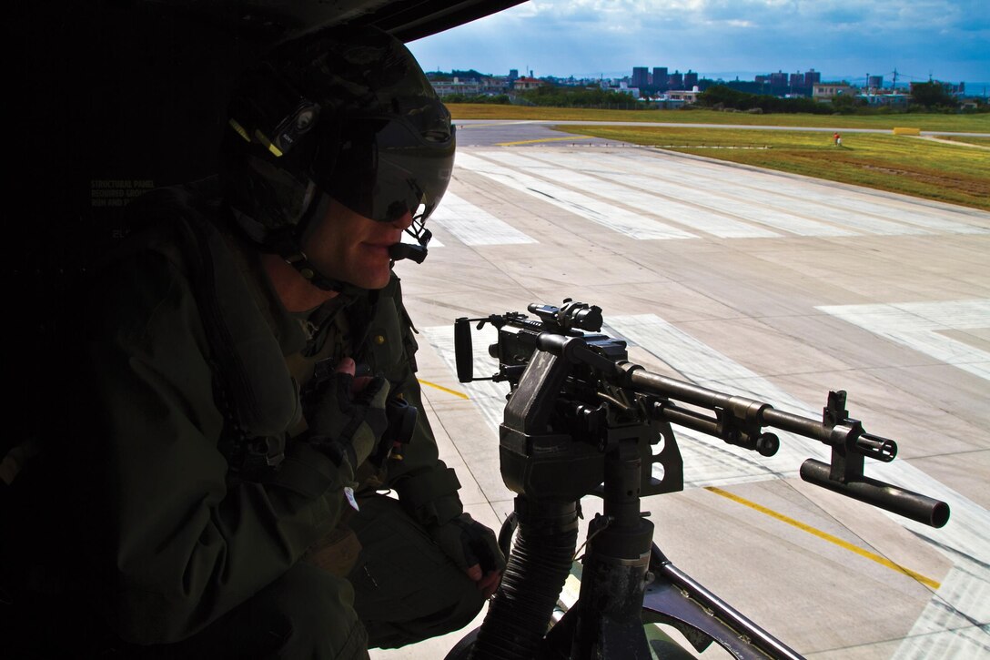 Sgt. Orrin G. Sanford observes the flight line out the side door of a UH-1Y Huey Jan. 16 as it flies toward Ie Shima Training Facility. Sanford honed his skills with the M240G medium machine gun  during forward air controller airborne practice at Ie Shima. As a gunner, Sanford is expected to provide suppressive fire in support of ground troops. Sanford is assigned to HMLA-367, currently assigned to VMM-265 (Reinforced), 31st MEU, III MEF. 