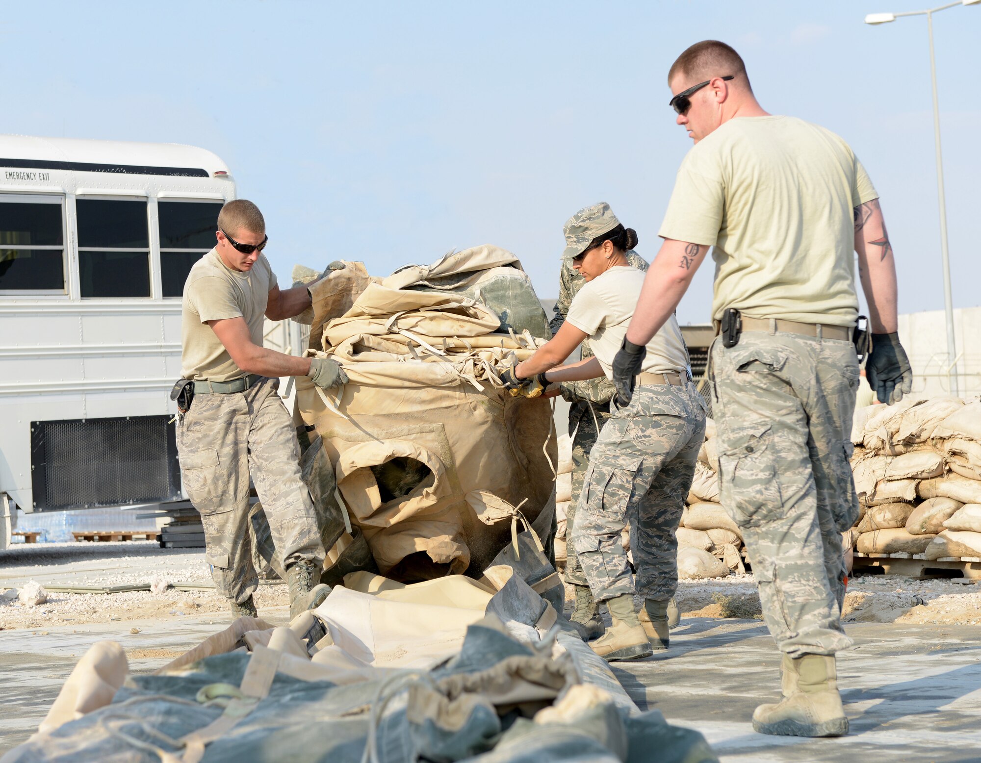 Airmen from the 379th Expeditionary Civil Engineer Squadron fold a tent during Operations Town Demobilization at Al Udeid Air Base, Qatar, Jan. 21, 2014. The 379th ECES leads the way to accomplish the project called Ops Town Demobilization with a crew of nearly 320 Airmen. The goal of the project is to move all equipment, personnel and temporary facilities in the area to a new location on base so the land can be returned to the host nation. (U.S. Air Force photo/Senior Airman Hannah Landeros) 