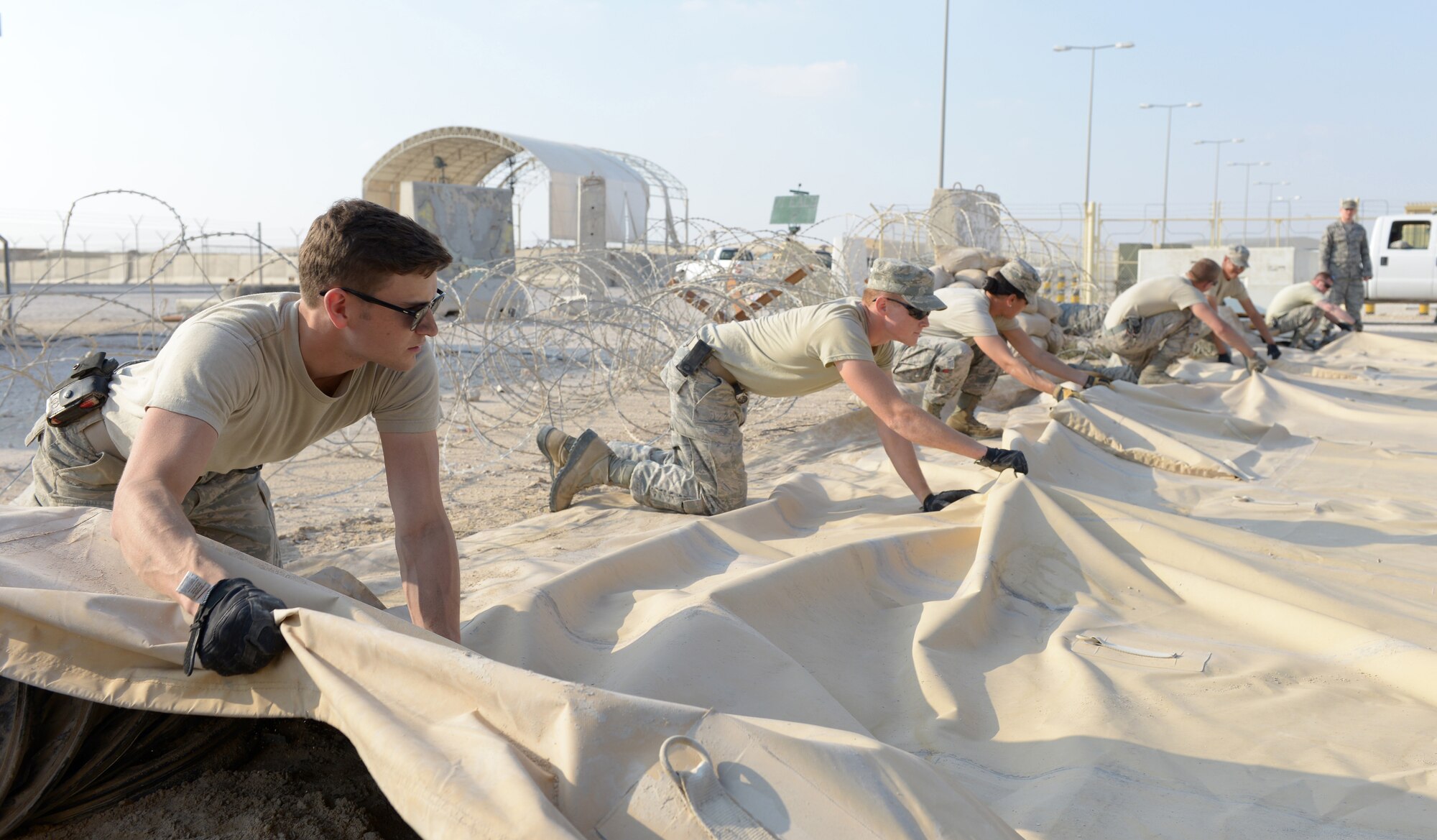 Airmen from the the 379th Expeditionary Civil Engineer Squadron fold a tent during Operations Town Demobilization at Al Udeid Air Base, Qatar, Jan. 21, 2014. The 379th ECES leads the way to accomplish the project called Ops Town Demobilization with a crew of nearly 320 Airmen. The goal of the project is to move all equipment, personnel and temporary facilities in the area to a new location on base so the land can be returned to the host nation. (U.S. Air Force photo/Senior Airman Hannah Landeros) 