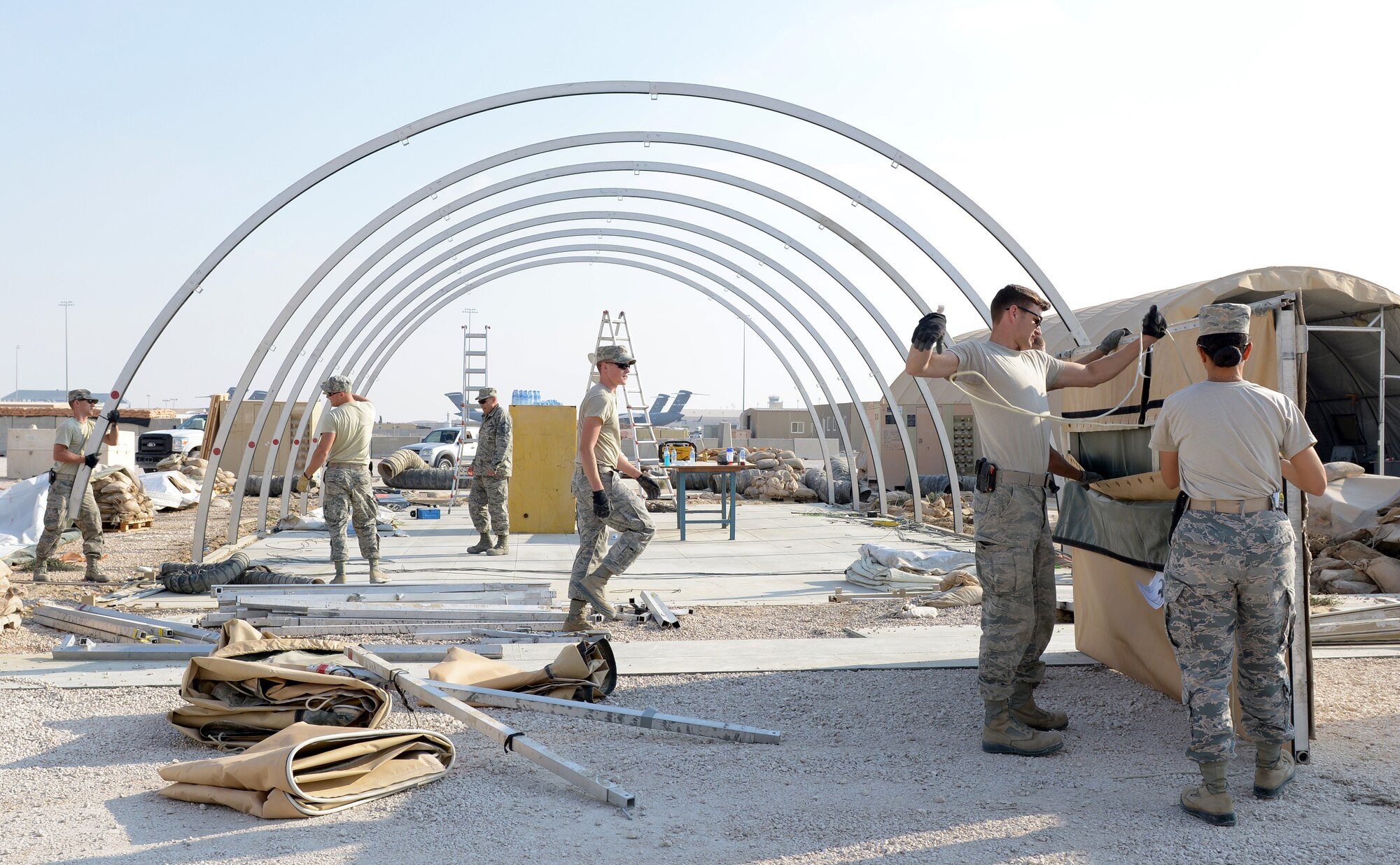 Airmen from the 379th Expeditionary Civil Engineer Squadron disassemble a tent during Operations Town Demobilization at Al Udeid Air Base, Qatar, Jan. 21, 2014. The 379th ECES leads the way to accomplish the project called Ops Town Demobilization with a crew of nearly 320 Airmen. The goal of the project is to move all equipment, personnel and temporary facilities in the area to a new location on base so the land can be returned to the host nation. (U.S. Air Force photo/Senior Airman Hannah Landeros) 
