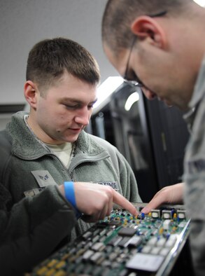 YOKOTA AIR BASE, Japan -- Senior Airman Jason Badia and Lucas Dugan, 374th Communications Squadron airfield systems technicians, inspect a radio processor card from a piece of equipment called the Enhanced Terminal Voice Switch. These cards ensure that air traffic controllers can communicate with aircraft in their area of responsibility. (U.S. Air Force photo by Staff Sgt. Andrea Salazar/Released)