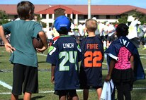 Four young football fans watch Team Sanders players practice during an Official National Football League Pro Bowl Practice on Earhart Field at Joint Base Pearl Harbor-Hickam, Hawaii, Jan. 23, 2014. The players were at JBPHH to practice for the Pro Bowl football game at Aloha Stadium in Honolulu, Hawaii, Jan. 26. Several children were selected from the sideline crowd of fans to go onto the field for a closer look and to interact with the players and trainers. (U.S. Air Force photo/Staff Sgt. Alexander Martinez)