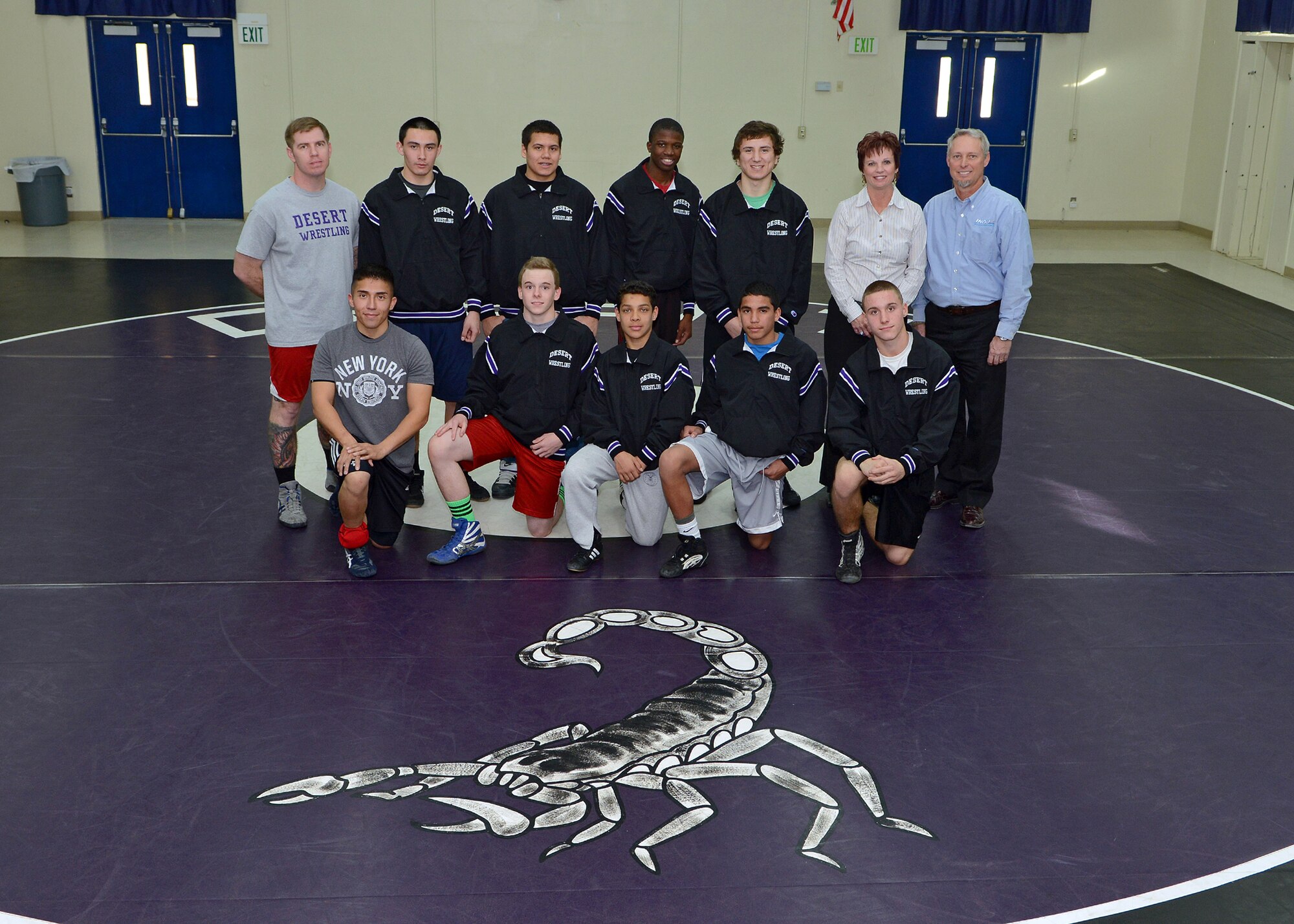 INQU president Ray Wilkens and INQU CEO Lori Wilkens (back row-right hand side) recently surprised and presented the Desert High School wrestling team with a set of warm-up uniforms that they donated during a team practice session on Jan. 21. Ray and Lori Wilkens had children who previously attended and graduated from DHS and wanted to give back to their local community by donating to one of the five self-funded sporting teams at DHS. (U.S. Air Force photo by Jet Fabara)
