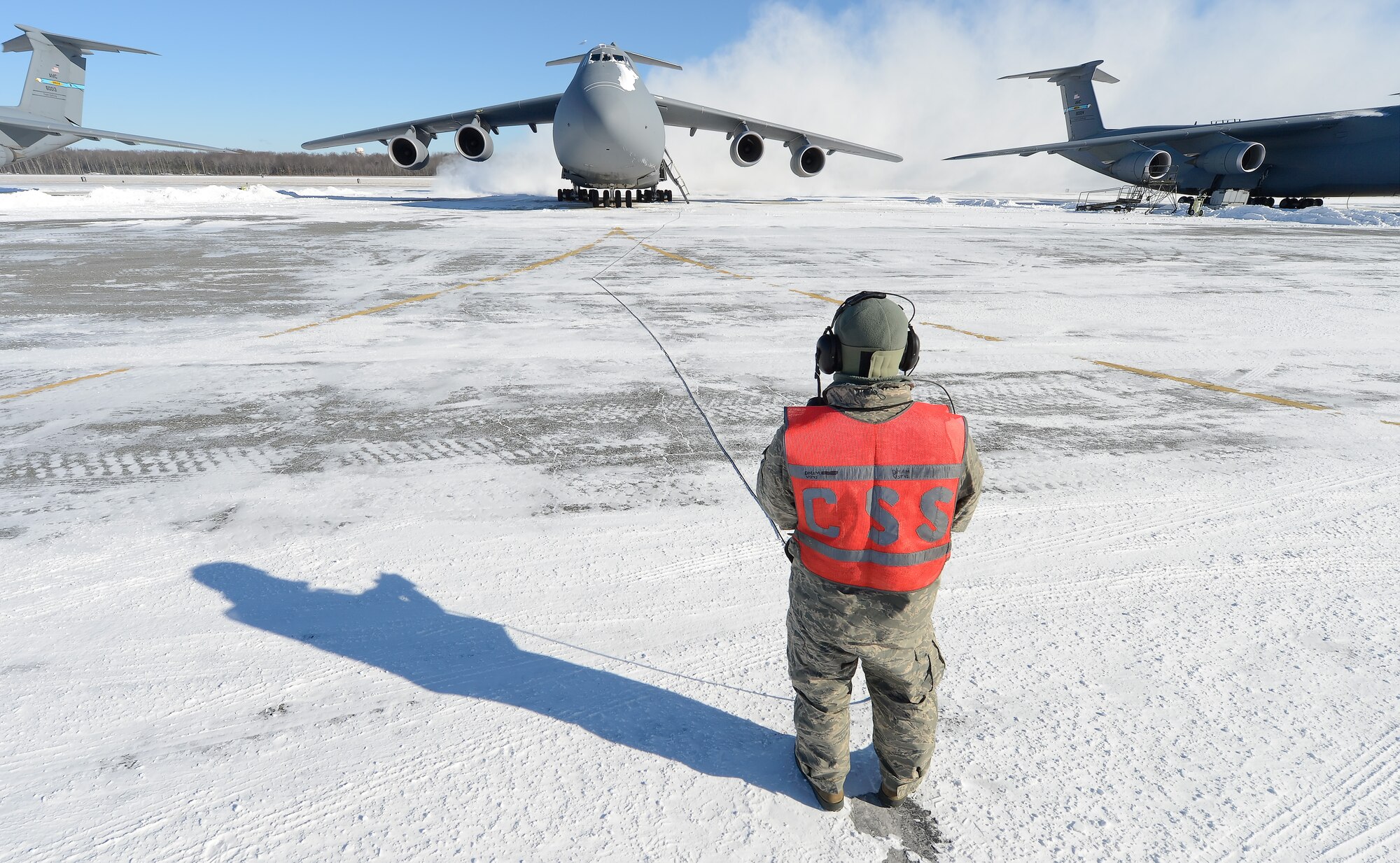 Airman 1st Class Jack Grimmett, 436th Aircraft Maintenance Squadron, jet engine mechanic, observes the engine run of a C-5M Super Galaxy from in front of the aircraft during a bleed-air operational check, Jan. 22, 2014, at Dover Air Force Base, Del. Long winter shadows are cast upon the snow-covered flightline while snow is blown up by the engines' exhaust. (U.S. Air Force photo/Greg L. Davis)