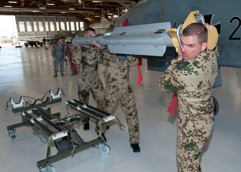 Master Sgt. Torsten Naujoks, Staff Sgt. Oliver Simmler and Staff Sgt. Christian Berg, German Air Force Flying Training Center crew chiefs, prepare an inert missile for a Tornado jet during a quarterly load crew competition at Holloman Air Force Base, N.M., Jan. 17. The GAF competed in the load crew competition to have their skills evaluated alongside the F-22 Raptor and MQ-9 Reaper load-crews. For the competition, points are awarded during the weapons loading, tool kit inspection and uniform inspection. (U.S. Air Force photo by Senior Airman Daniel Liddicoet/Released)