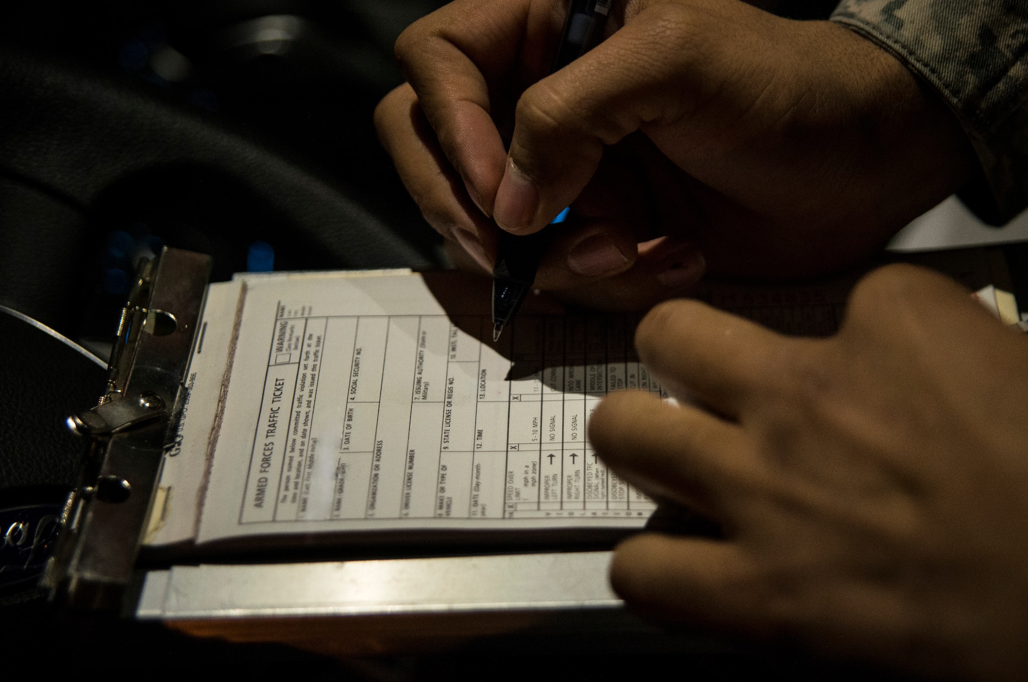 Airman 1st Class Trey Weston, 628th Security Forces Squadron entry controller to search, writes a ticket for a motorist suspected of speeding on base Dec. 22, 2013, at Joint Base Charleston – Air Base, S.C. 628th SFS patrolmen write tickets for speeding, parking violations and other motor vehicle violations on the Air Base and Weapons Station.  (U.S. Air Force photo/ Senior Airman Dennis Sloan)