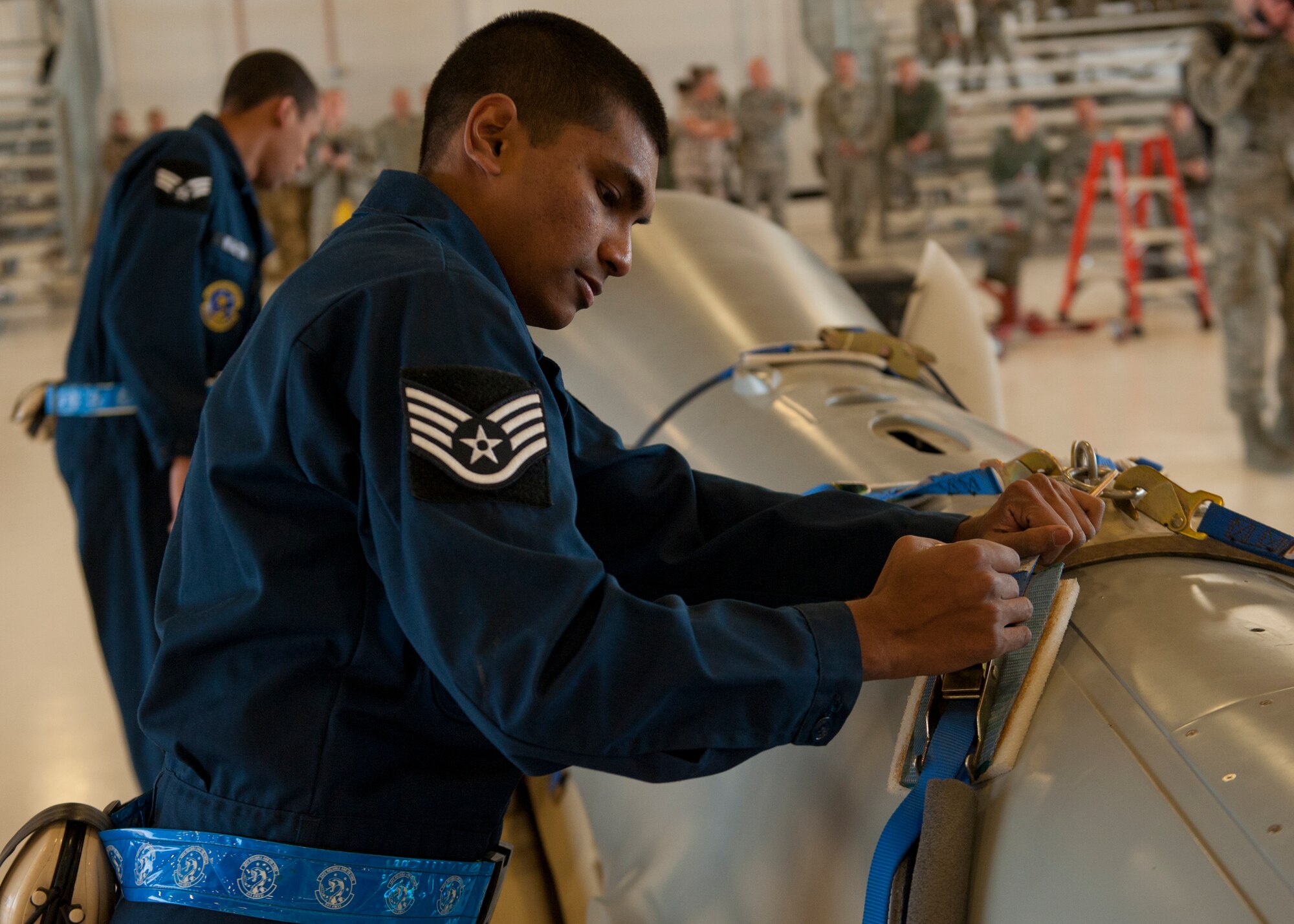 Staff Sgt. Ronald Suchit, 6th Aircraft Maintenance Unit dedicated crew chief, removes the straps from an MQ-1 Predator during a build-team demonstration at Holloman Air Force Base, N.M., Jan. 17. The MQ-1 build team demonstrates the airmen’s ability to build and prepare an MQ-1 after delivery. The build team travels to different locations to showcase the expedient process of assembly, which on average takes just over half an hour to complete. (U.S. Air Force photo by Airman 1st Class Aaron Montoya / Released)