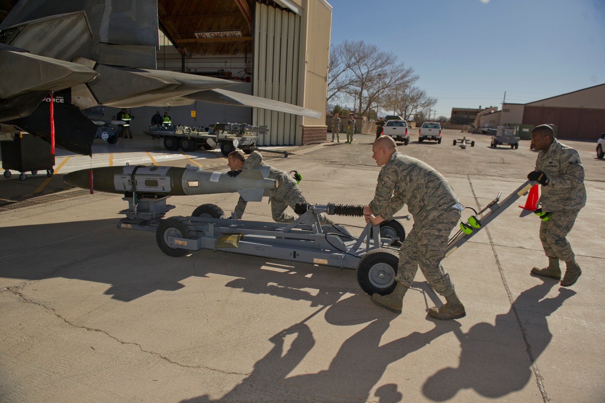 Senior Airman Andrew Guise, Airman 1st Class Brady Lene and Airman 1st Class Orlandus Ray, all 49th Aircraft Maintenance Squadron weapons-load-crew members, prepare to load an inert missile for a quarterly load-crew competition at Holloman Air Force Base, N.M., Jan. 17. This was the last load crew competition that the F-22 Raptor will participate in at Holloman. The F-22 load-crew competed to have their skills evaluated alongside the MQ-9 Reaper and the German Air Force Tornado load-crews. For the competition, points were awarded for weapons loading, tool kit inspection and uniform inspection. (U.S. Air Force photo by Airman 1st Class Chase Cannon/Released)