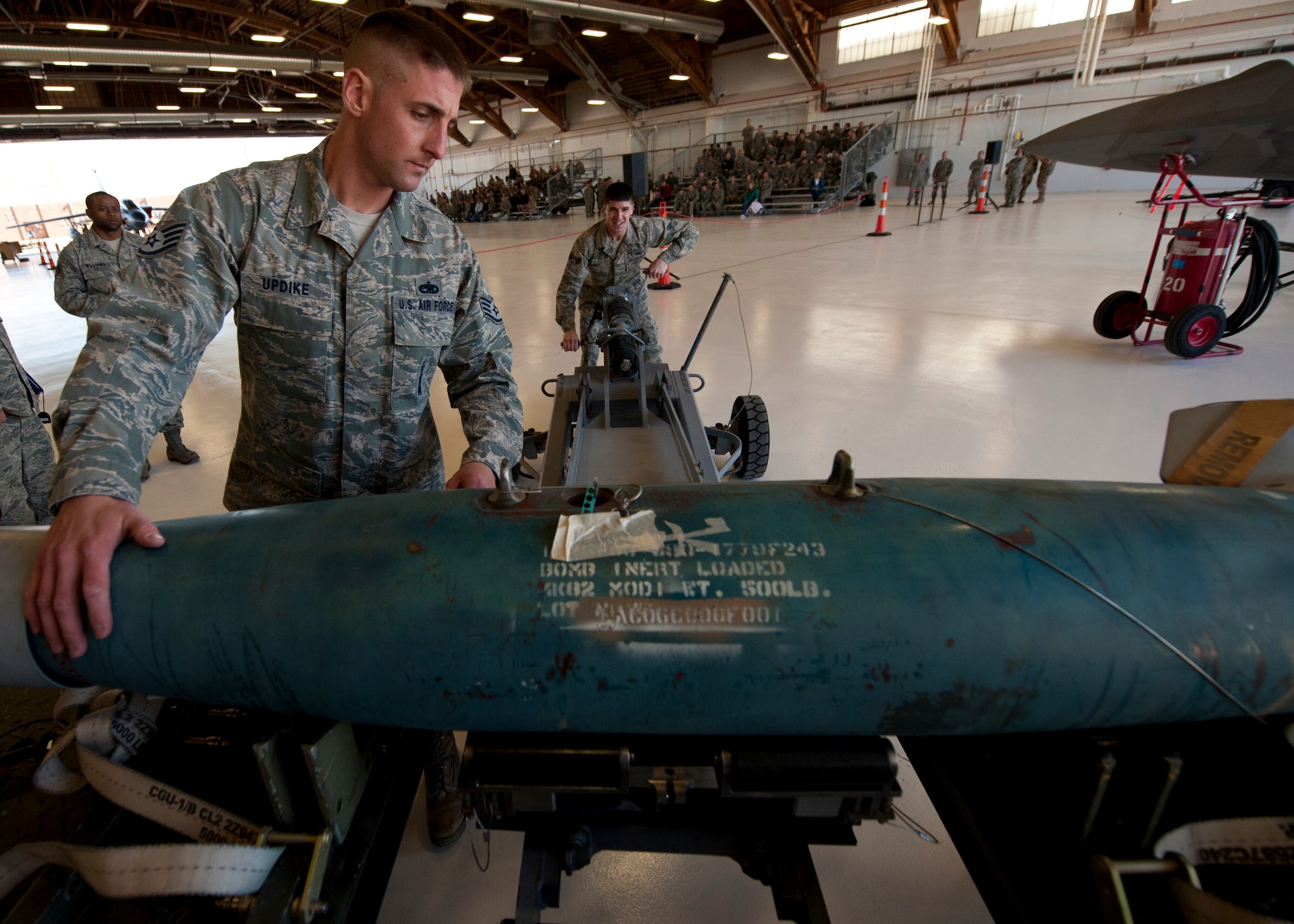 Staff Sgt. Aaron Updike and Senior Airman Thomas Lahut from the 849th Aircraft Maintenance Squadron, prepare to load an inert bomb onto an MQ-9 Reaper during a quarterly load crew competition at Holloman Air Force Base, N.M., Jan. 17. The MQ-9 load-crew competed in the competition to have their skills evaluated alongside the F-22 Raptor and German Air Force load crews. For the competition, points are awarded during the weapons loading, tool kit inspection and uniform inspection. (U.S. Air Force photo by Airman 1st Class Aaron Montoya / Released)