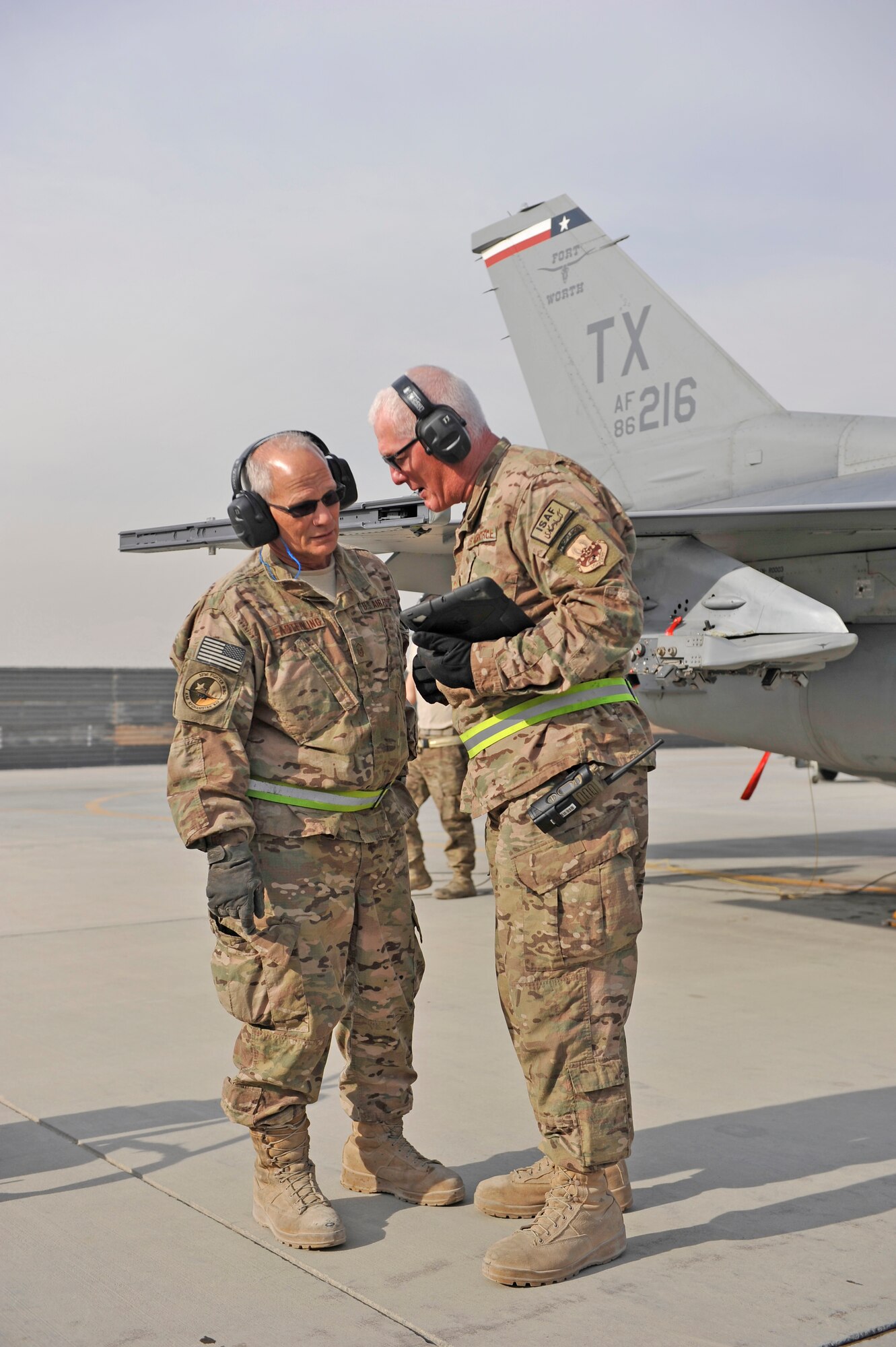 U.S. Air Force Master Sgt. Doyle Easterling confers with Senior Master Sgt. Paul Jordan during an F-16 engine test run at Bagram Airfield, Afghanistan, Jan. 20, 2014. Both are deployed out of Carswell Joint Reserve Base in Fort Worth, Texas to Bagram, and will be retiring this year after a combined 78 years of military service. (U.S. Air Force photo by Senior Master Sgt. Gary J. Rihn/Released)