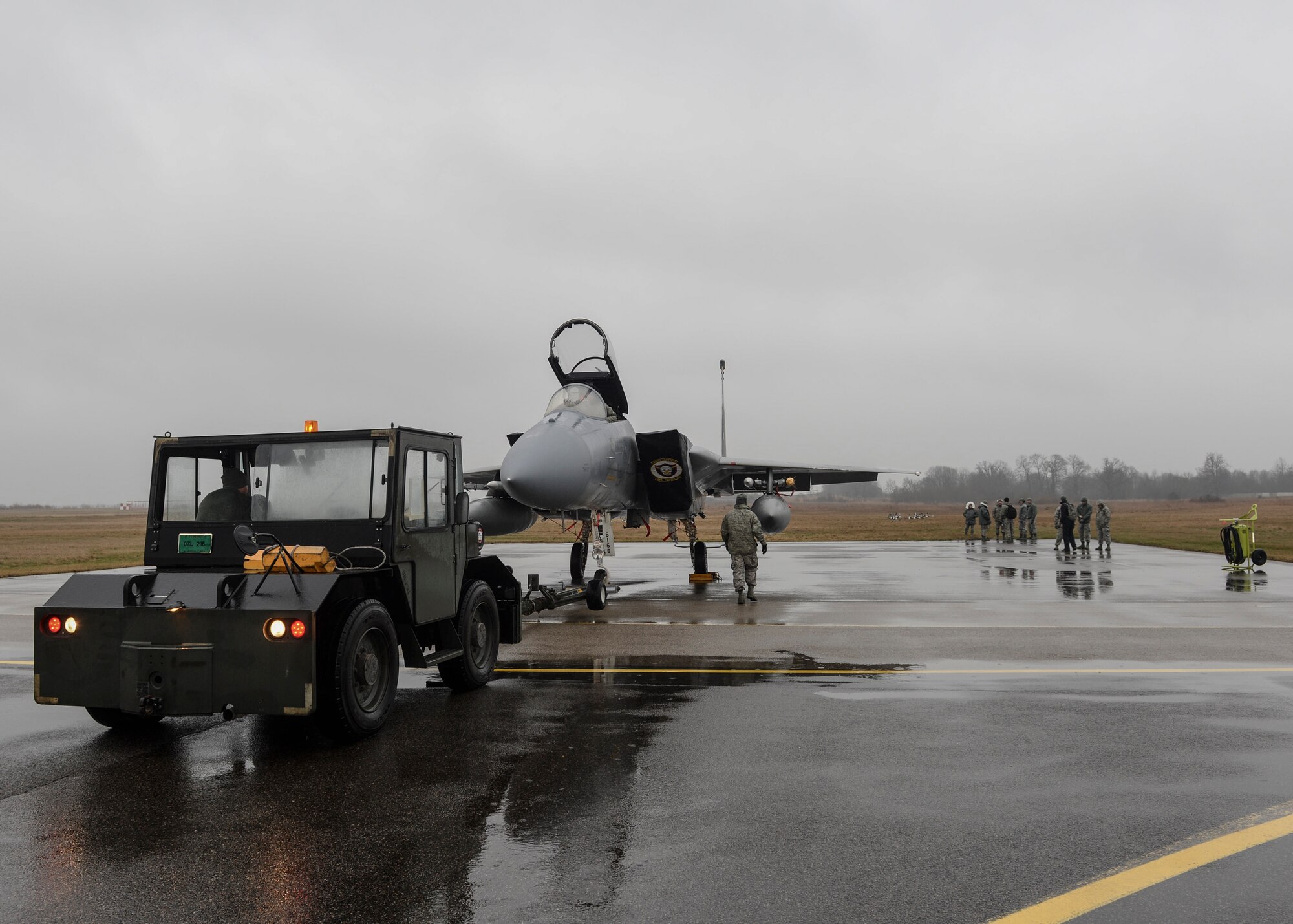 A flightline tractor tows an F-15C Eagle into position before an engine test at Siauliai Air Base, Lithuania, Jan. 4, 2014. During the Baltic Air Policing mission, the 48th AEG installed an expeditionary trim pad to provide an anchor for engine checks. (U.S. Air Force photo by Airman 1st Nigel Sandridge/Released)