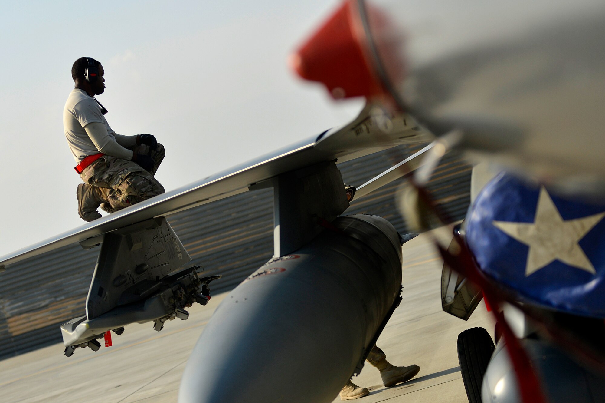A U.S. Air Force Airman assigned to the 455th Expeditionary Aircraft Maintenance Squadron sits on the wing of an F-16 Fighting Falcon at Bagram Airfield, Afghanistan, Jan. 22, 2014. Airmen worked to remove the engine of the aircraft due to a bad hydraulic line. (U.S. Air Force photo by Senior Airman Kayla Newman/Released)