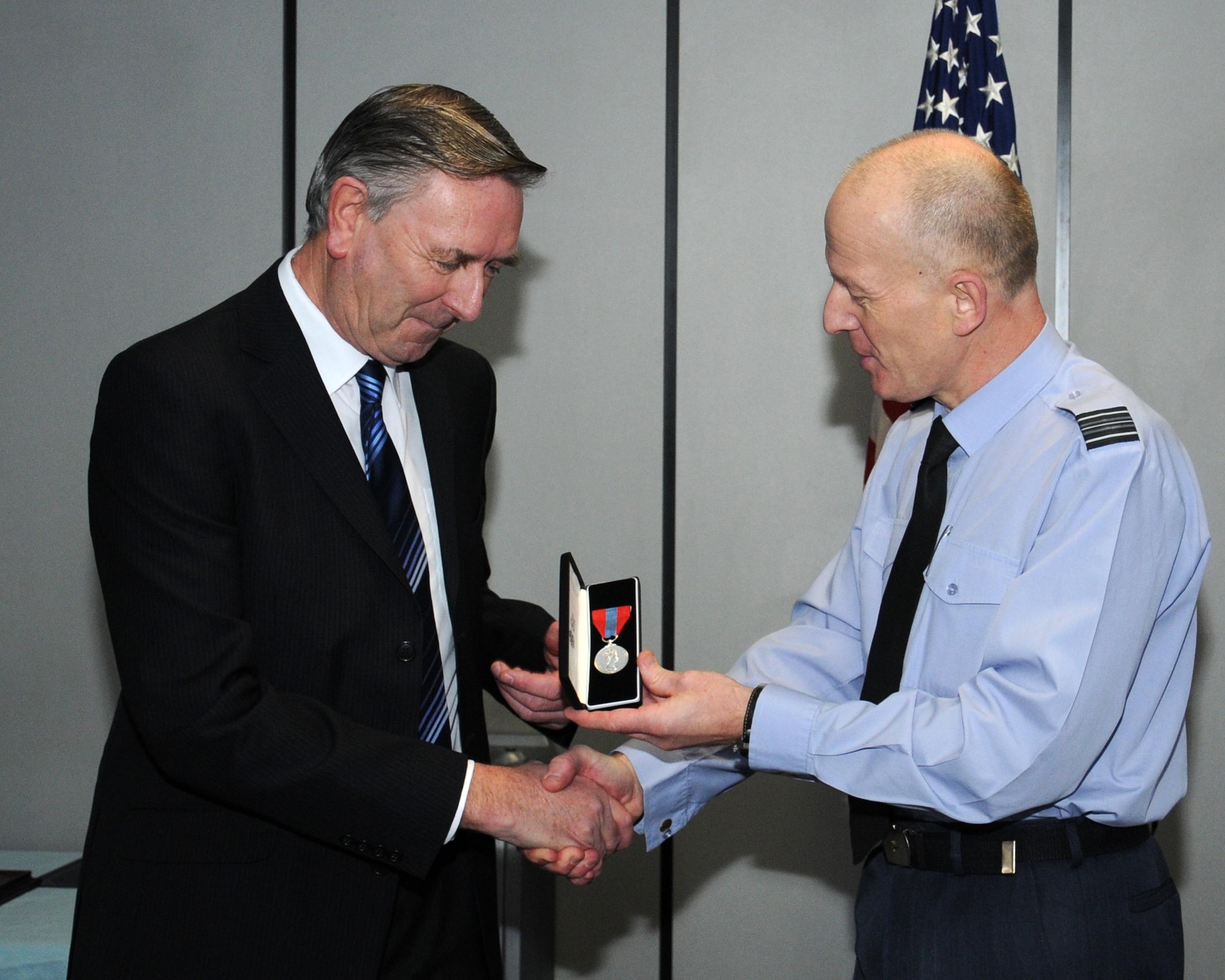RAF Sqn. Ldr. Rick Fryer, right, RAF Mildenhall station commander, presents the Imperial Service Medal to Colin Grubb Jan. 21, 2014, on RAF Mildenhall, England. Grubb worked at the 727th Air Mobility Squadron on RAF Mildenhall for 39 years with an impeccable record. Grubb worked as a freight warehouse technician and load planner in the Air Mobility Command’s sole aerial port in the British Isles. (U.S. Air Force photo by Gina Randall/Released) 