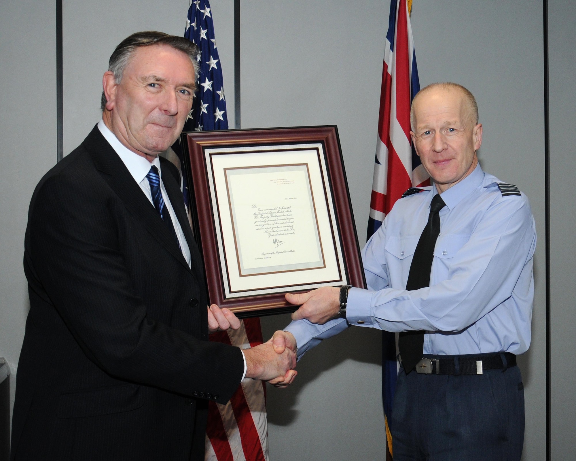 RAF Sqn. Ldr. Rick Fryer, right, RAF Mildenhall station commander, presents the Imperial Service Medal to Colin Grubb Jan. 21, 2014, on RAF Mildenhall, England. Grubb worked at the 727th Air Mobility Squadron on RAF Mildenhall for 39 years with an impeccable record. During his tenure, Grubb saw the reorganization of the squadron four times, the height and end of the Cold War, integration of Eastern Europe into NATO, the development of the European Union and RAF Mildenhall’s support to Operation Desert Storm, peacekeeping operations in Bosnia and Macedonia, the wars in Iraq and Afghanistan as well as numerous humanitarian and global crisis support operations. (U.S. Air Force photo by Gina Randall/Released) 