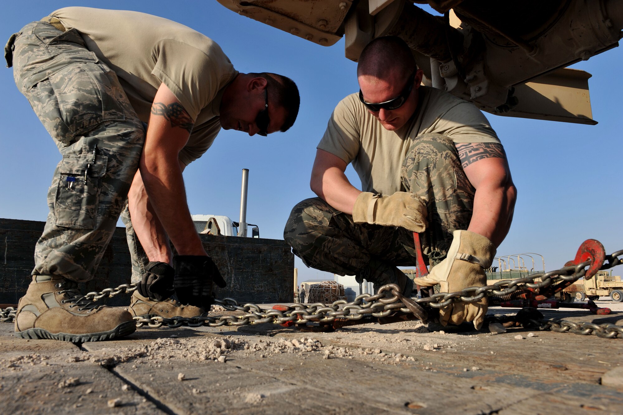 Senior Airman Hunter Spears and Senior Airman Shane Zimmerman prepare to secure a U.S. Army M939 5-Ton vehicle at Al Udeid Air Base, Qatar, Jan. 17, 2014. The 379th Expeditionary Logistics Readiness Squadron was tasked to move 51 vehicles and miscellaneous pieces of equipment from the former 11th Air Defense Artillery Brigade, 1st Battalion, 43rd Air Defense Artillery Regiment site, to a collection point for further distribution. All vehicles were inoperable and had to be towed or loaded onto a flatbed trailer for movement. This was the final push in the complete movement of the 1-43rd ADA from their old site to their new location. The move took three days to complete. Spears is a 379th ELRS vehicle operator deployed from Minot Air Force Base, N.D., and a Fort Smith, Ark., native.  Zimmerman is a 379th ELRS vehicle operator deployed from Eglin Air Force Base, Fla., and a Bear Creek, N.C., native. (U.S. Air Force photo by Master Sgt. David Miller)
