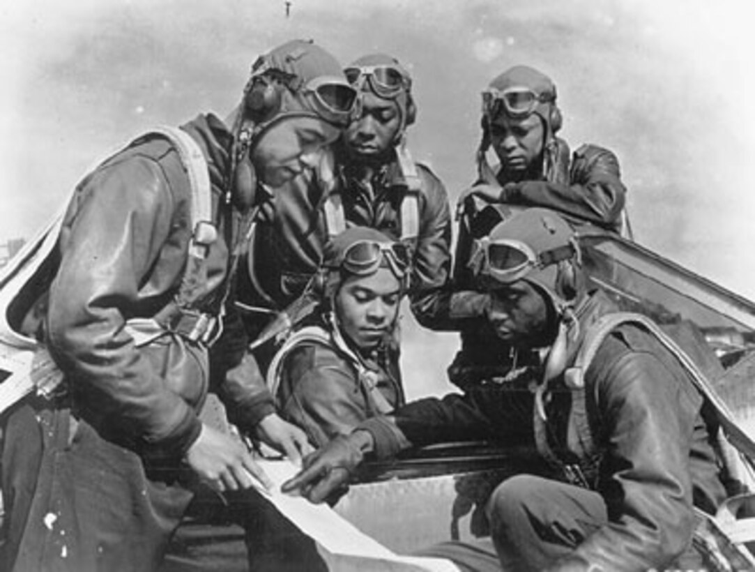 A group of Black pilots look at a document.