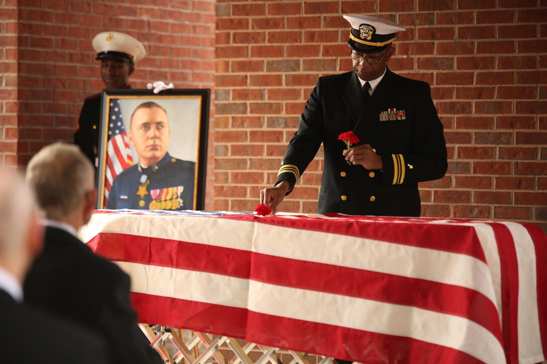 Lt. Cmdr. Raynard Allen, Navy chaplain for Headquarters and Service Battalion, Marine Corps Recruit Depot Parris Island, places a poppy on the casket of Medal of Honor recipient John James McGinty III during his funeral Jan. 23, 2014, at Beaufort National Cemetery in Beaufort, S.C. McGinty, a decorated Vietnam War hero and Parris Island veteran, died Jan. 17, 2014, in his home in Beaufort at the age of 73.