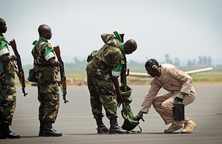 Rwandan soldiers wait in line to have their weapons inspected by Staff Sgt. Curtis McWoodson (right), before getting on a C-17 Globemaster III Jan. 19, 2014, at the Kigali airport, Rwanda. U.S. forces will transport 850 Rwandan soldiers and more than 1,000 tons of equipment into the Central African Republic to aid French and African Union operations against militants during this three-week operation. McWoodson is a member of the 627th Security Forces Squadron Phoenix Raven, tasked to protect the C-17 based out of Joint Base Lewis-McChord Air Force Base, Wa. (U.S. Air Force photo/Staff Sgt. Ryan Crane)
